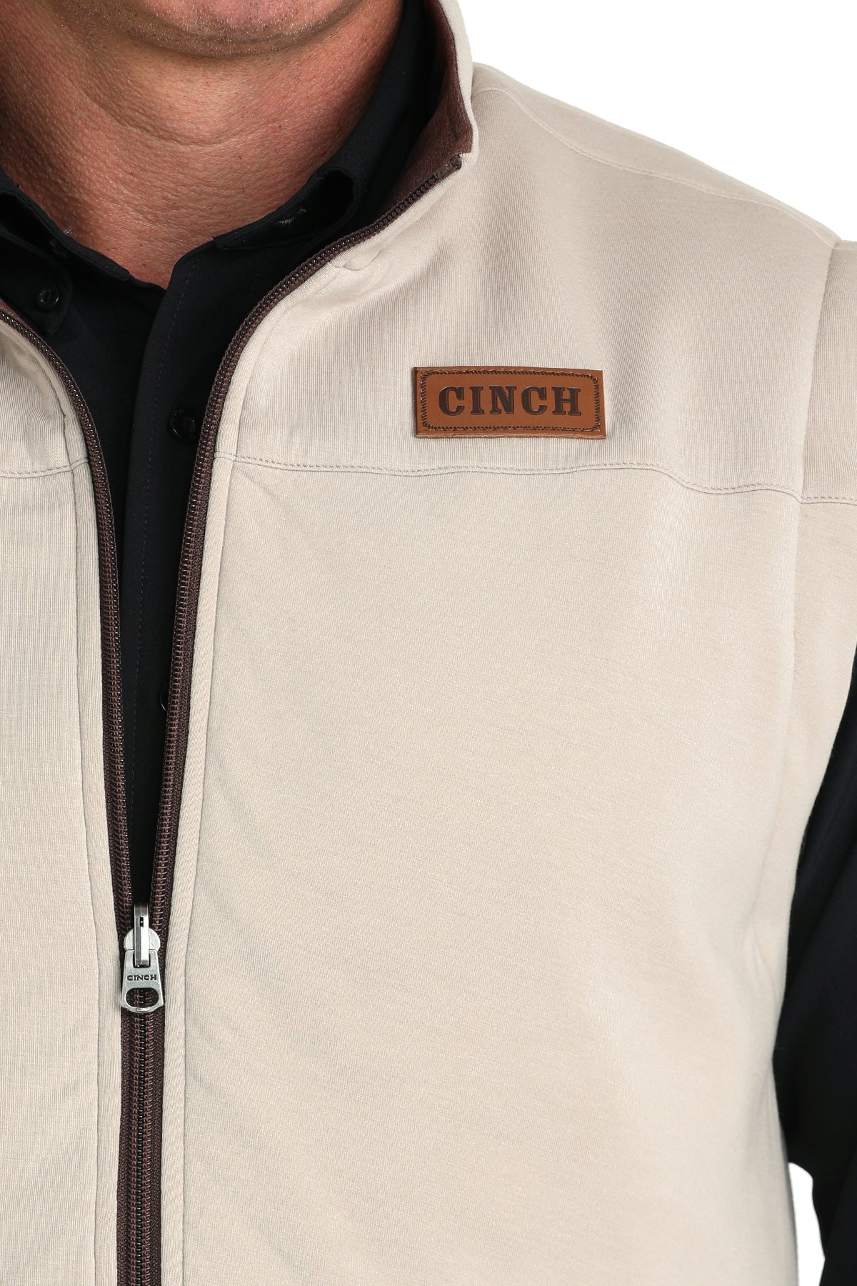 Close-up of a man wearing a beige vest with a black undershirt