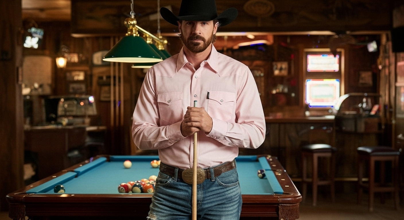 Man in a cowboy hat and pink shirt holding a pool cue in a bar setting
