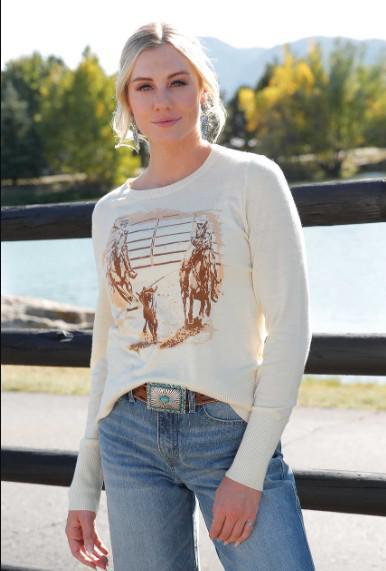 Woman outside wearing a cream colored long sleeve shirt and jeans