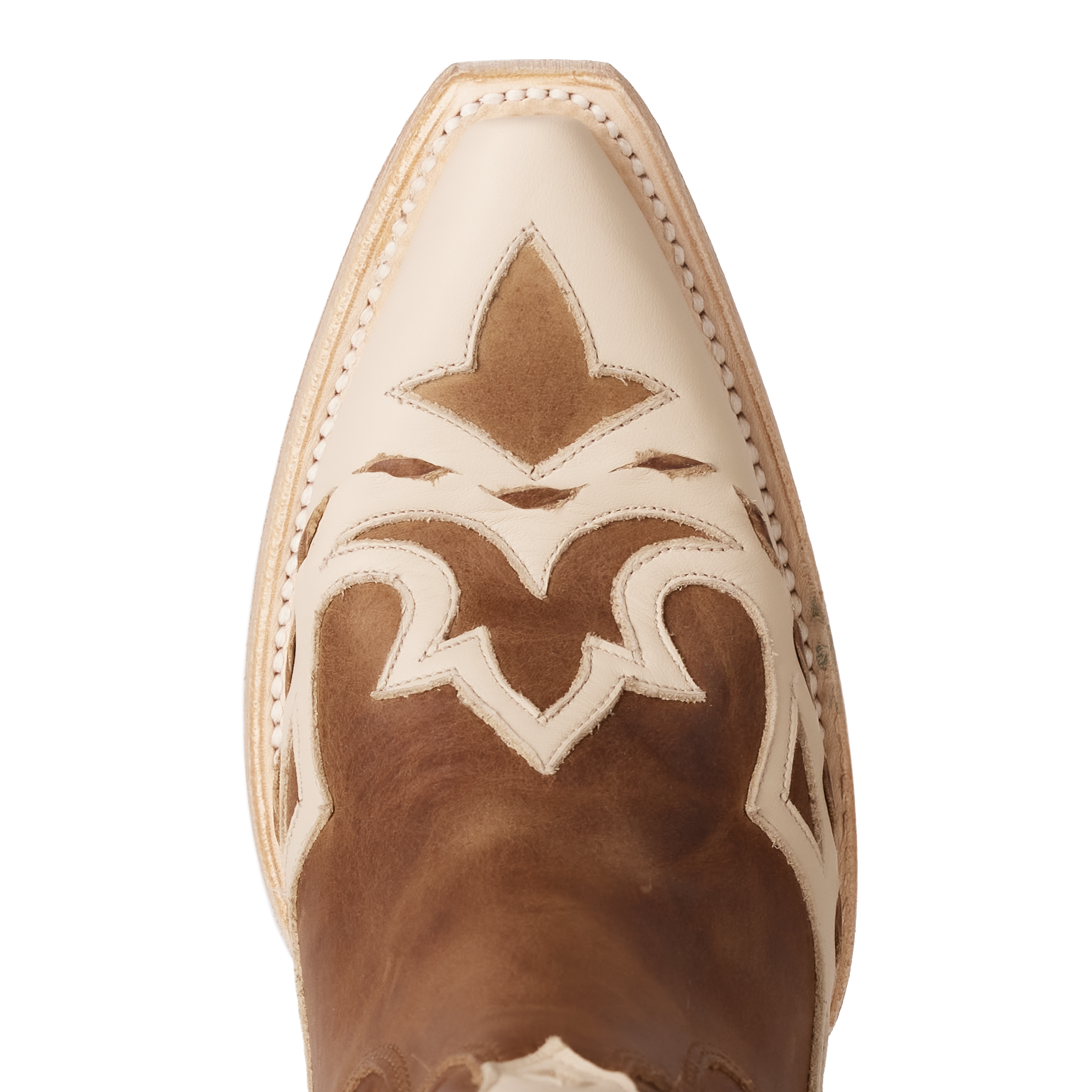 Close-up of a cowboy boot toe featuring a pointed cream-colored tip with intricate cream overlays stitched onto a rich brown leather base in a decorative western pattern