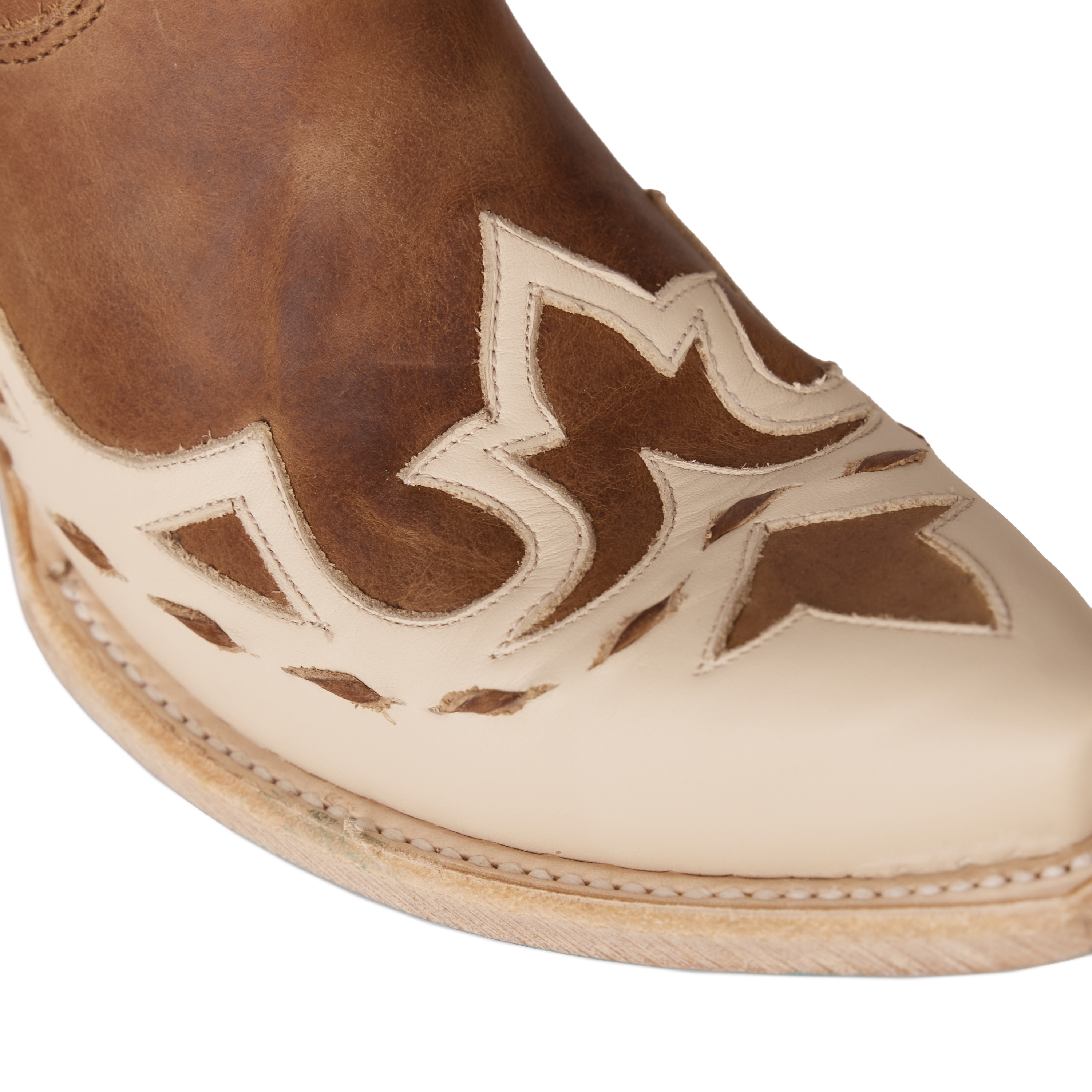 Close-up of a cowboy boot’s cream-colored toe with layered brown leather inlays