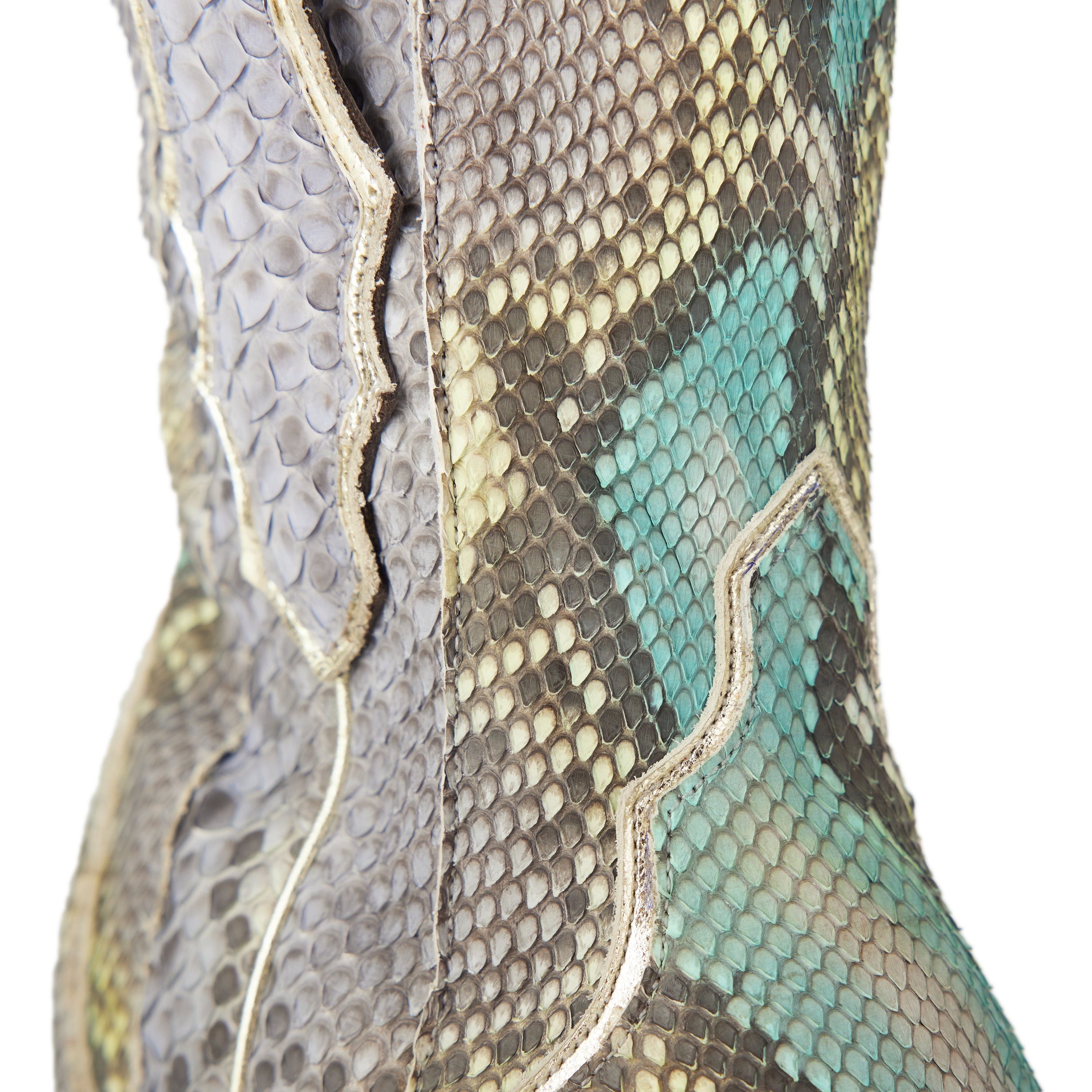 Close-up of a snakeskin cowboy boot highlighting the textured scale pattern in shades of gray, tan, and turquoise with light-colored stitching outlining a curved western design