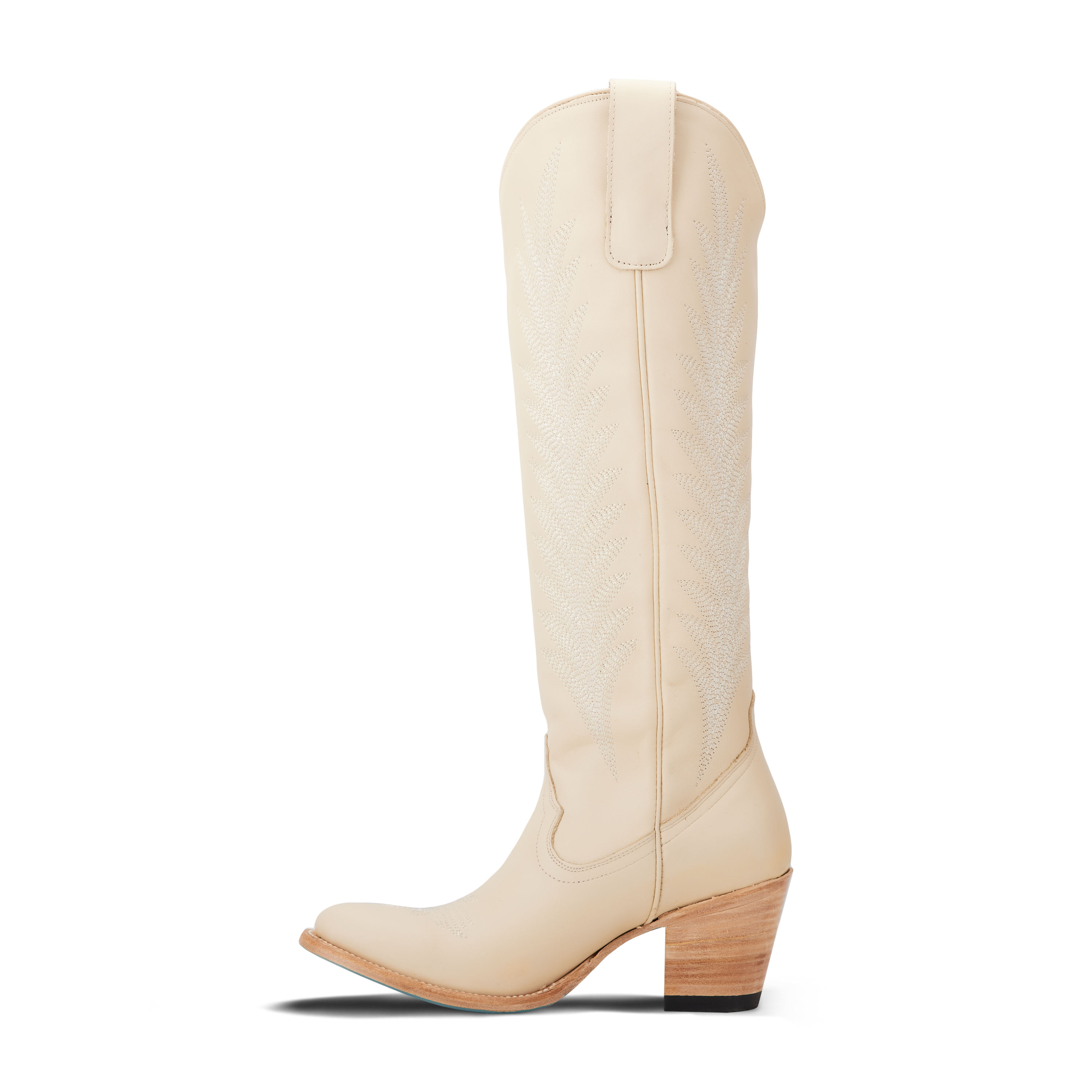 Side view of a tall cream colored cowboy boot with decorative stitching on the shaft, pull tabs at the top, a pointed toe, and a stacked heel
