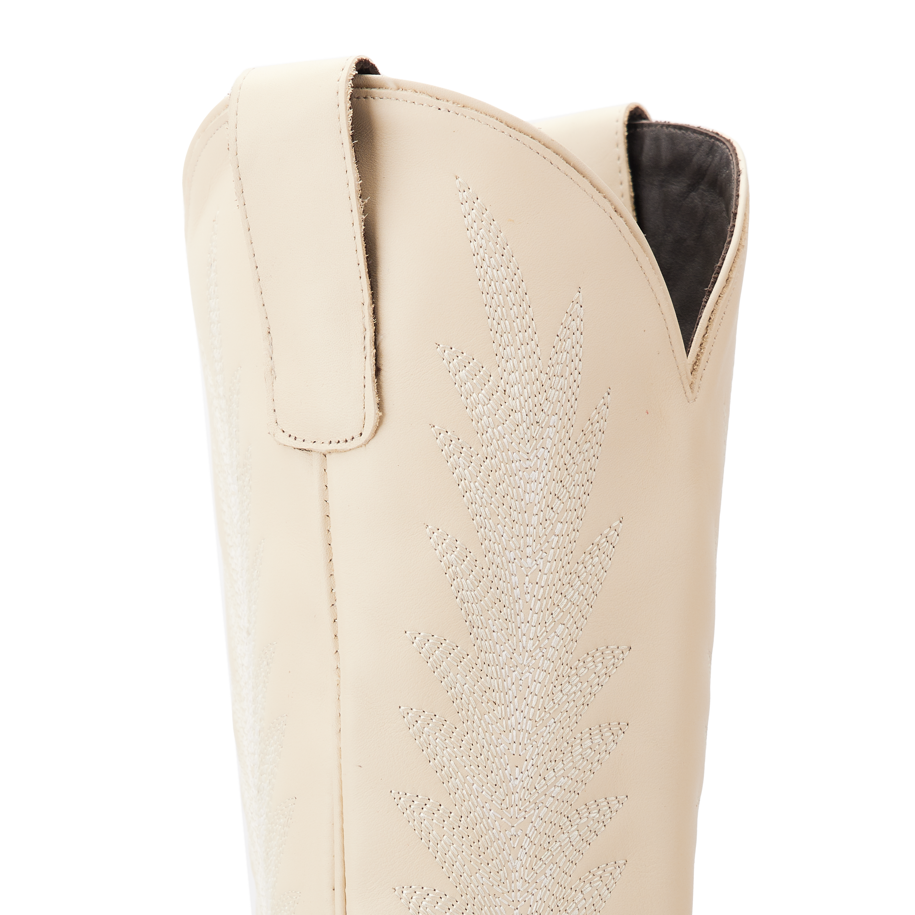 Close-up of the upper shaft of a cream colored cowboy boot featuring detailed stitching in a leafy pattern and side pull tabs