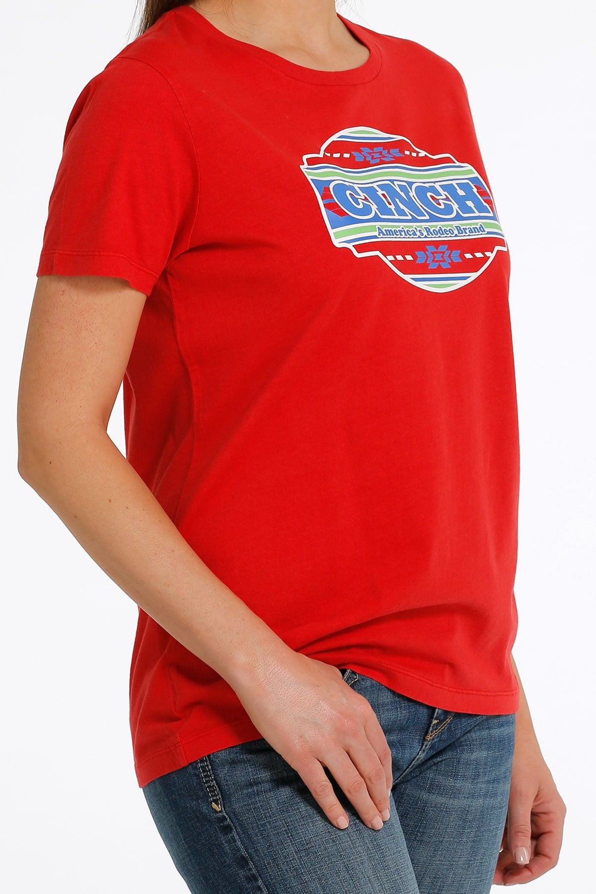 Front angled view of a woman wearing a red t-shirt with a large 'Cinch' graphic in the middle  and jeans