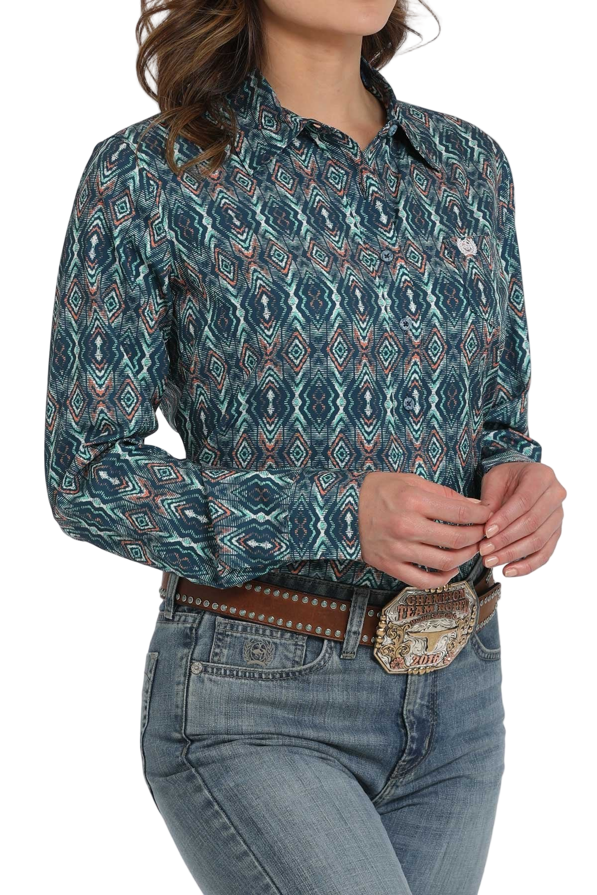 Woman wearing a teal patterned long-sleeve shirt paired with light-wash jeans and a studded brown belt with a decorative buckle