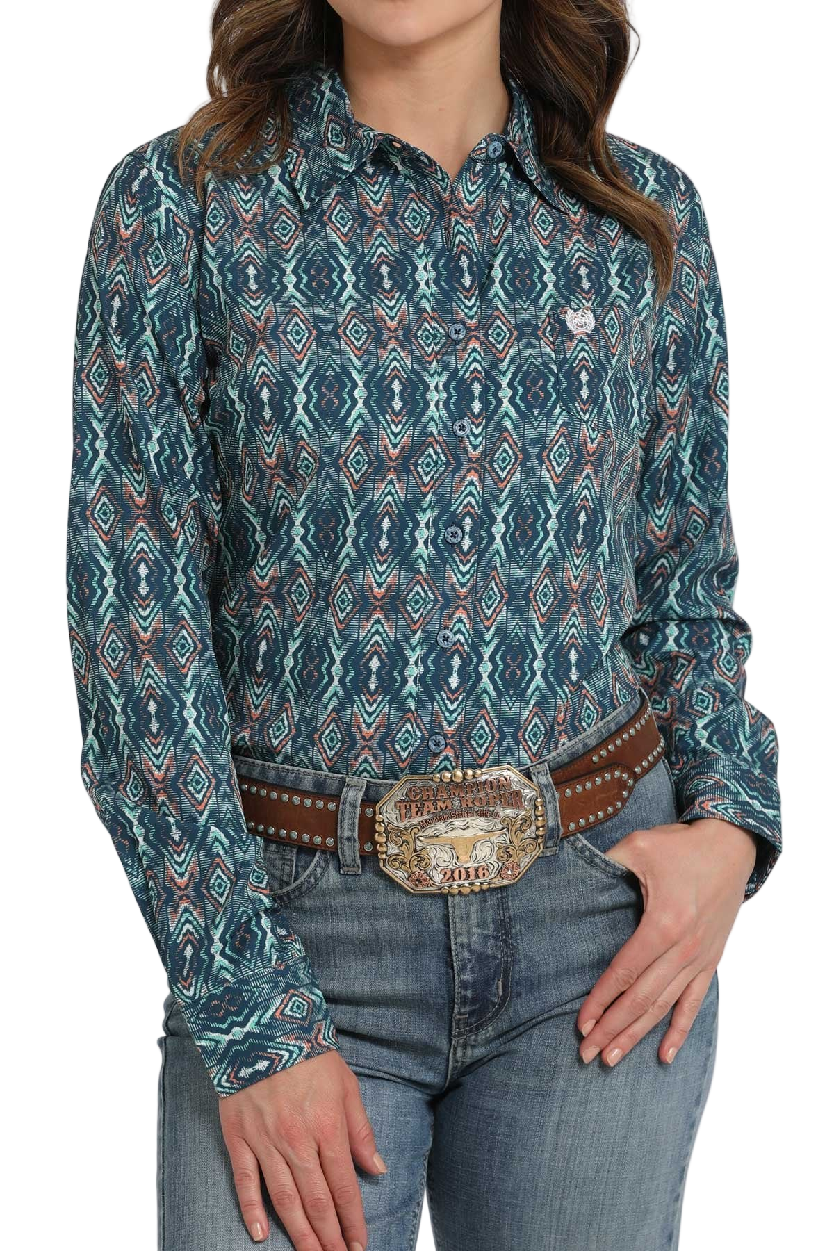 Woman wearing a teal patterned long-sleeve shirt paired with light-wash jeans and a studded brown belt with a decorative buckle