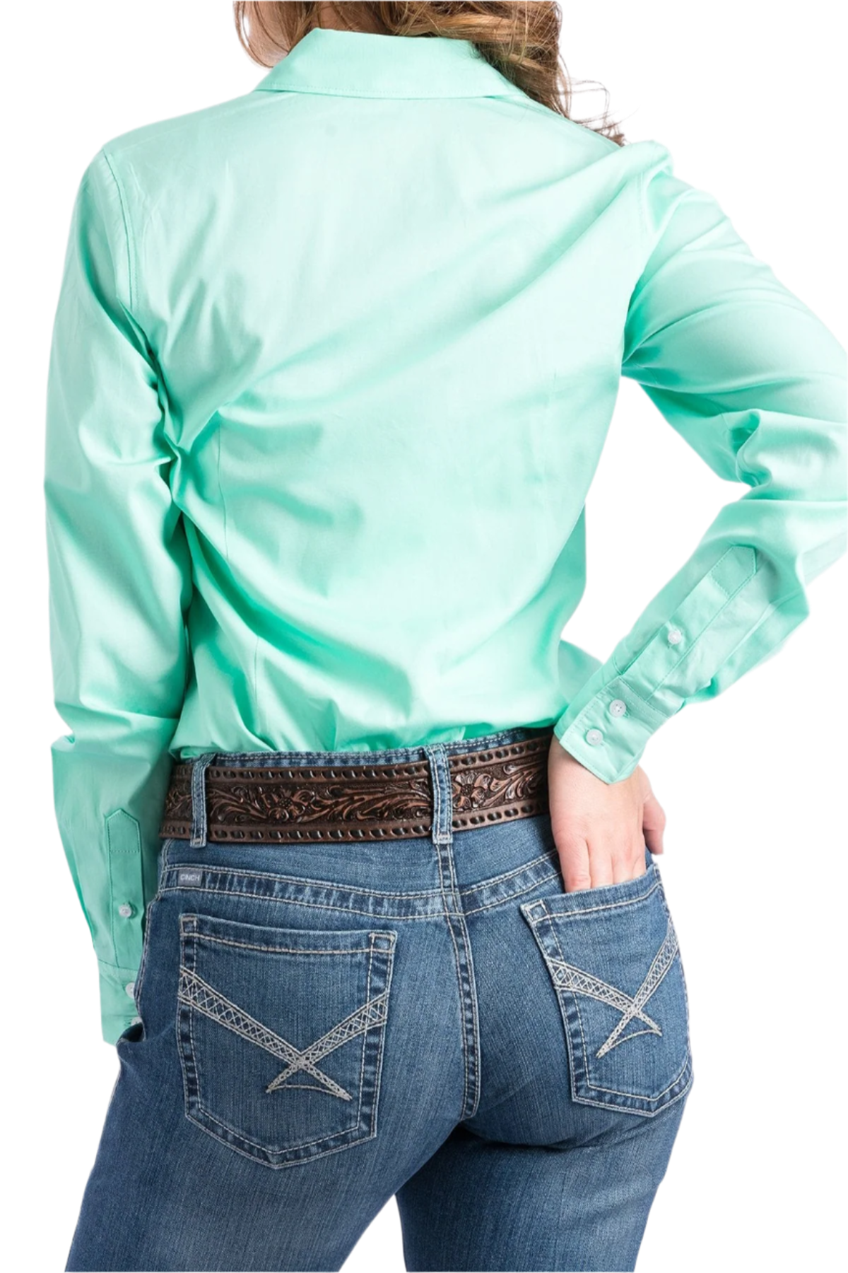 Back view of a woman wearing a mint green button down shirt, with jeans and a western belt