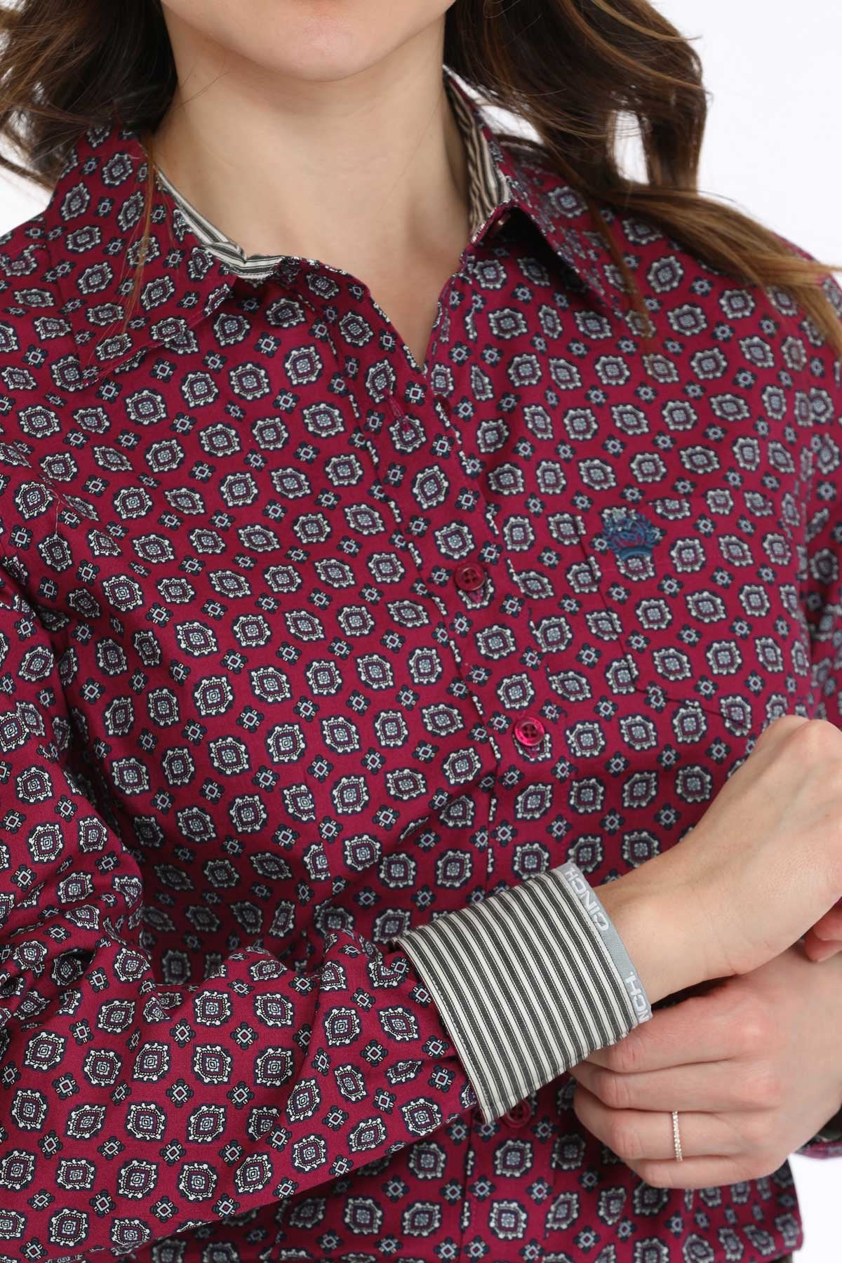 Close-up of a woman wearing a maroon patterned long-sleeve button-up shirt with contrasting cuffs
