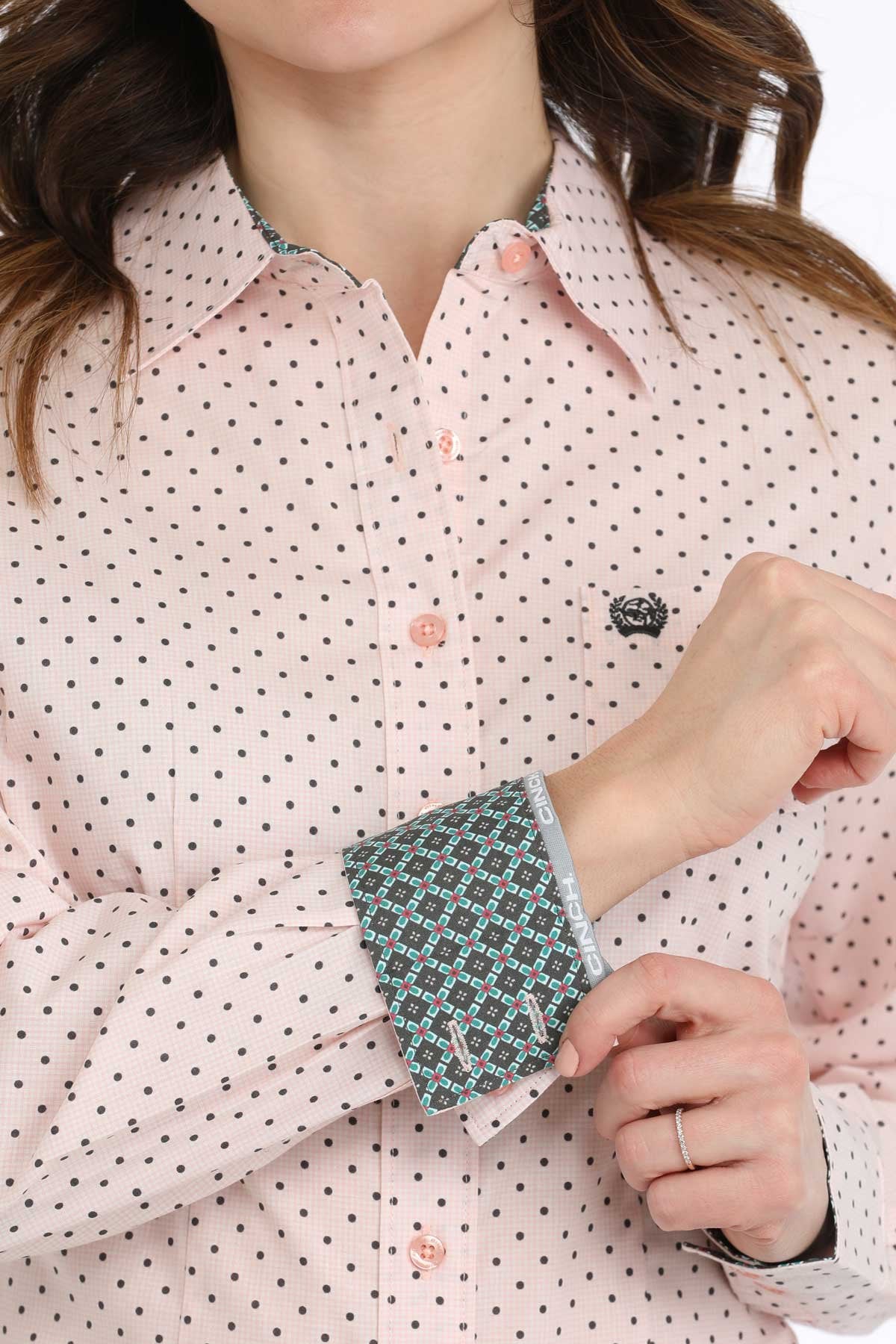 Close-up of a person wearing a pink polka dot shirt with patterned cuffs.