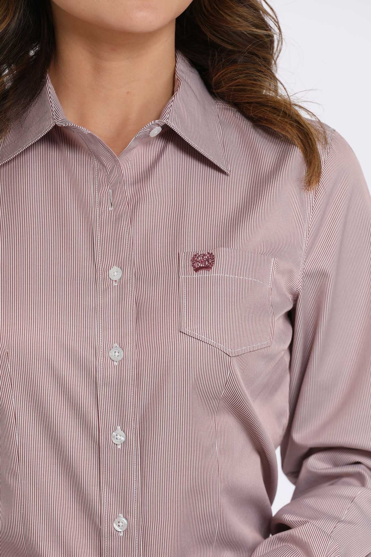 Close-up of a woman wearing a light pink satin button-down shirt with a front pocket displayed on a white background.