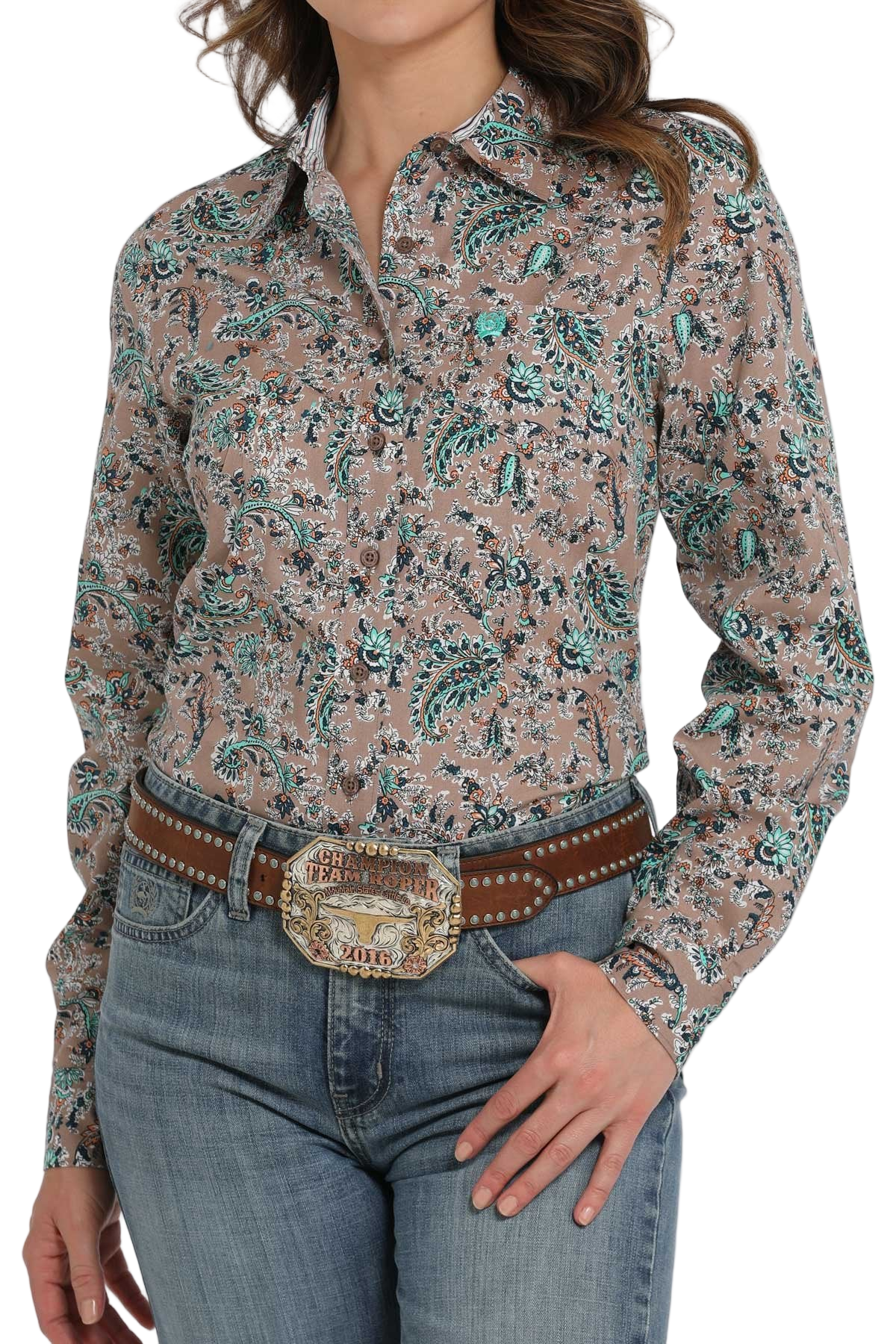 Woman wearing a patterned long-sleeve button-down shirt, paired with jeans and a large western belt buckle