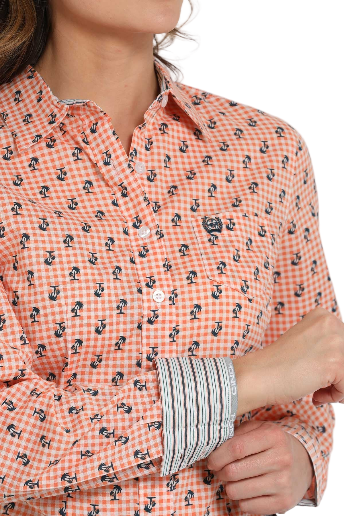 Close-up of a woman wearing a peach patterned button-down shirt with printed contrast cuffs