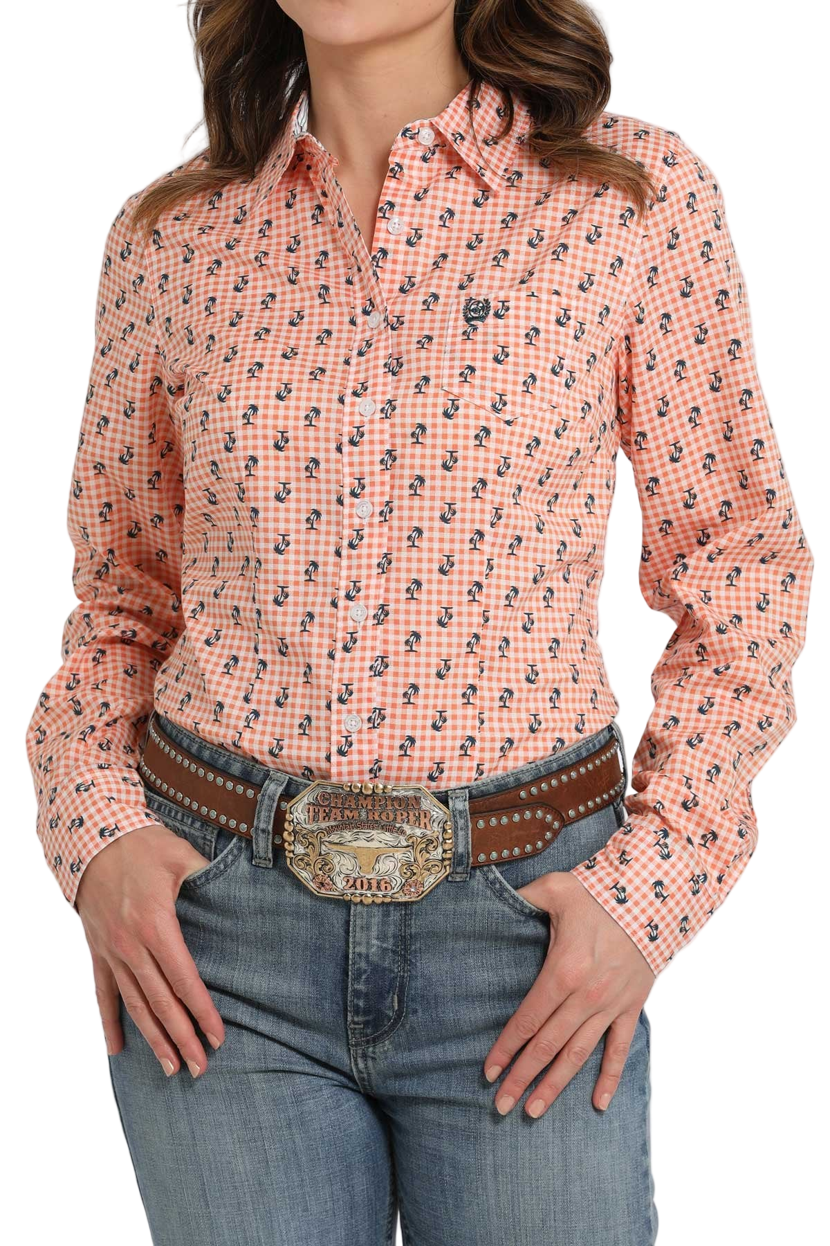 Woman wearing a peach patterned button-down shirt, paired with a tooled belt and denim jeans