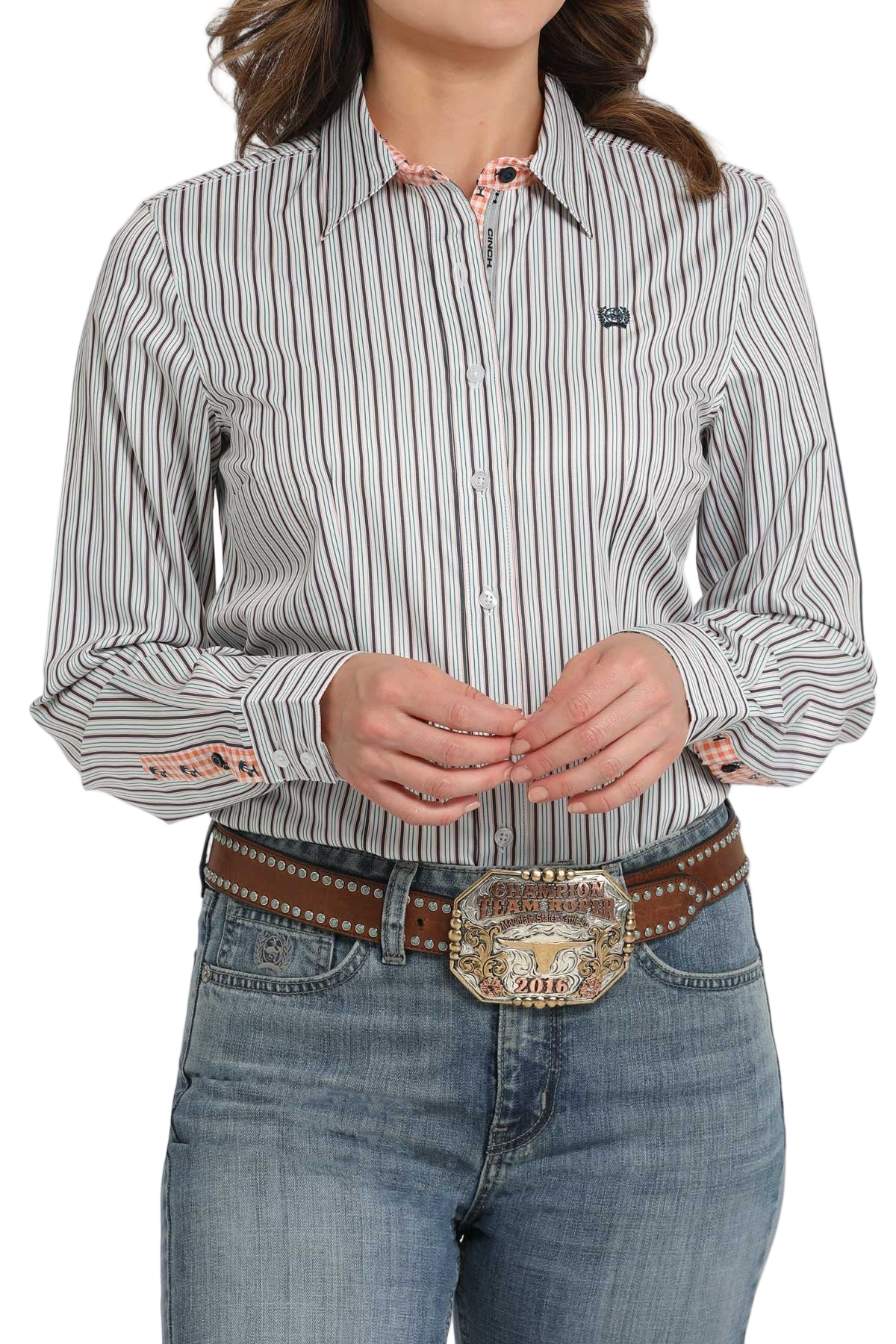 Woman wearing a light patterned long-sleeve button shirt, paired with light-wash jeans and a brown belt with a large decorative buckle