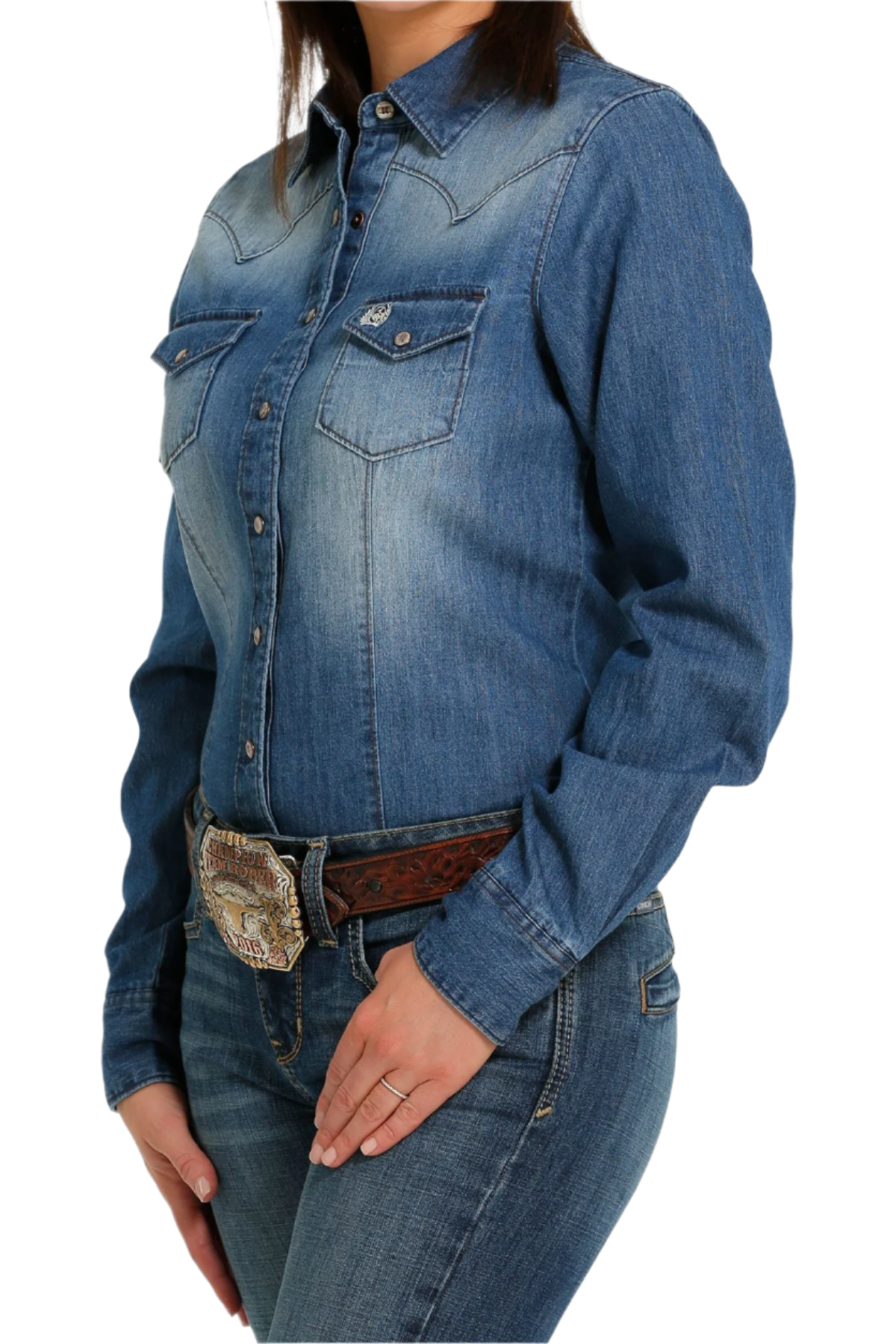 Woman wearing a dark stone wash button down shirt with jeans and a western belt