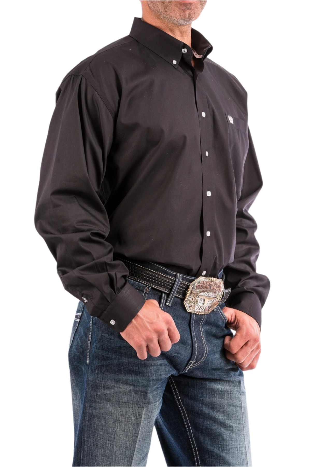 A man wearing a long sleeve black western shirt and blue jeans, with a belt and buckle visible.