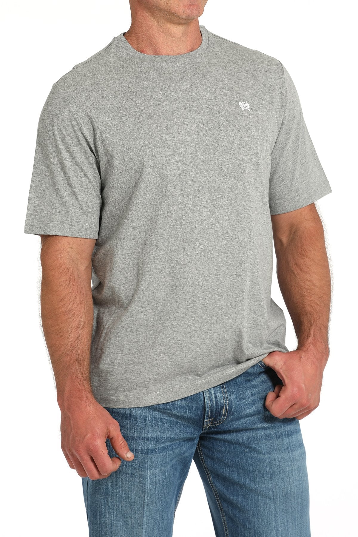Side angled view of a man wearing a gray short-sleeve t-shirt with a small white chest logo, paired with blue jeans displayed on a white background.