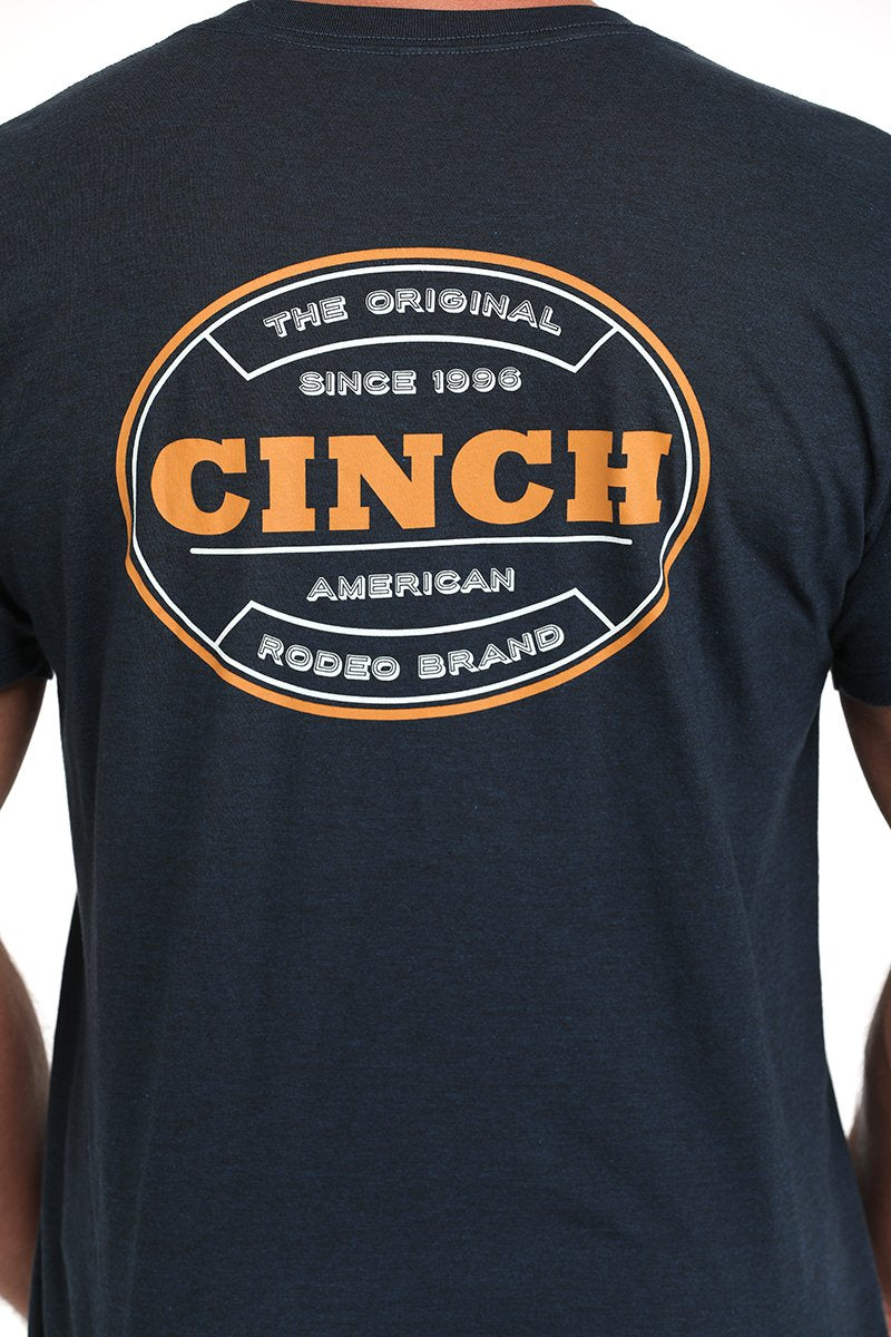 Close-up of a back view of a man wearing a dark navy short-sleeve t-shirt with a large circular CINCH logo in orange and white displayed on a white background.