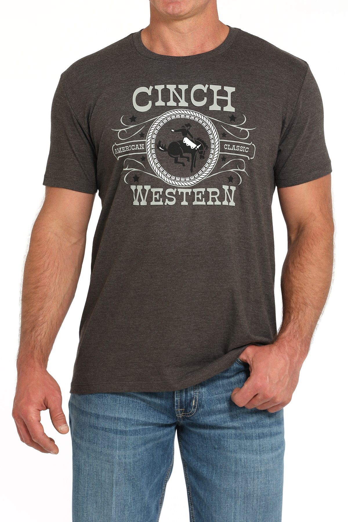 Front view of a man wearing a gray short-sleeve t-shirt with a large CINCH Western graphic, paired with blue jeans displayed on a white background.