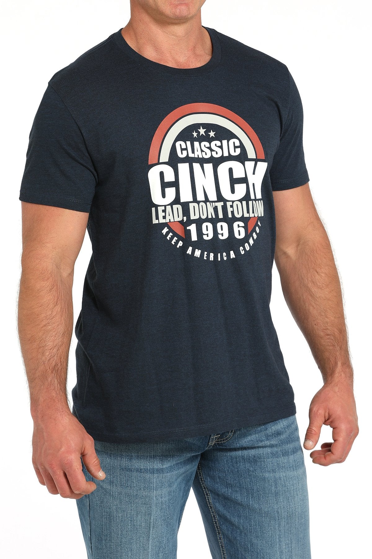 Side angled view of a man wearing a navy blue short-sleeve t-shirt with a circular CINCH graphic, paired with blue jeans displayed on a white background.