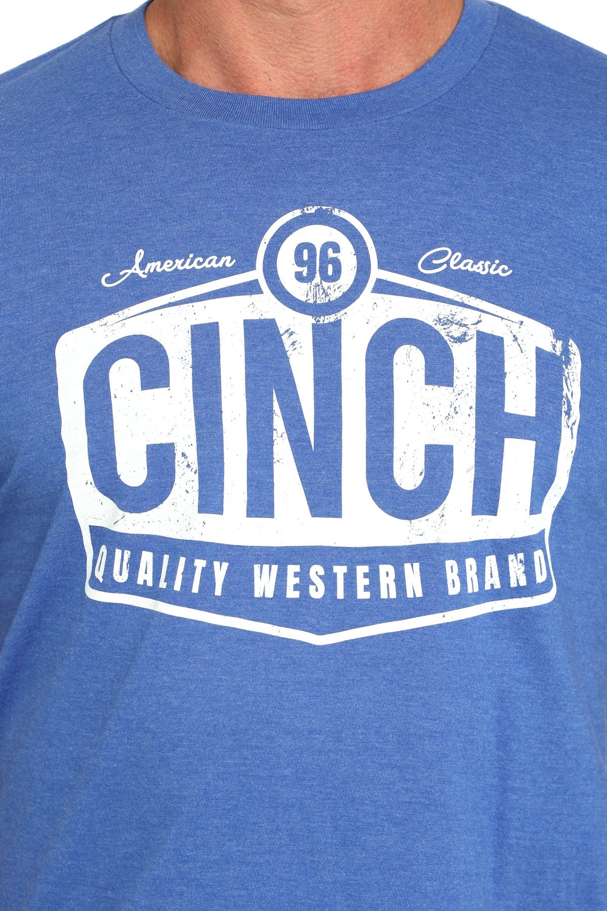 Close-up view of a blue short-sleeve t-shirt with a large white CINCH graphic and 'Quality Western Brand' text displayed on a white background