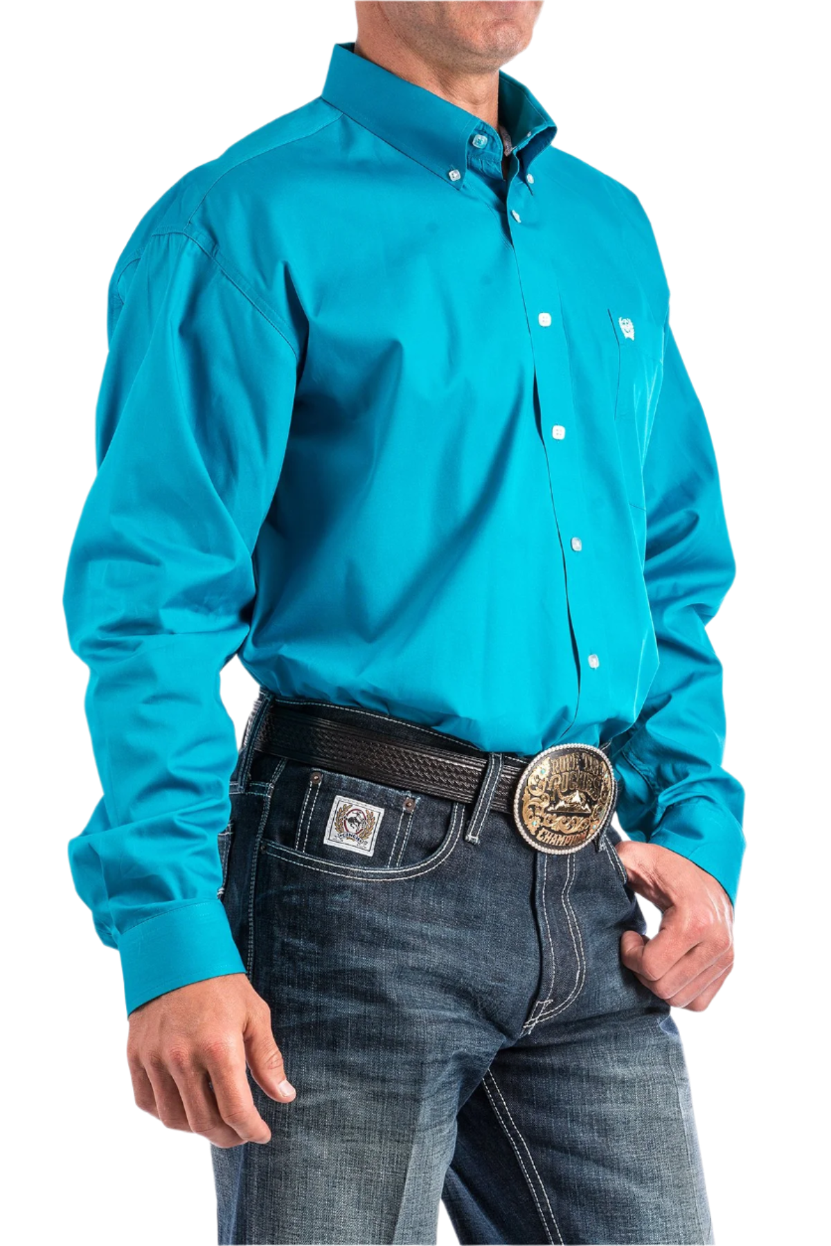 A man wearing a long-sleeve teal blue button-down shirt and blue jeans, with a belt and buckle visible.