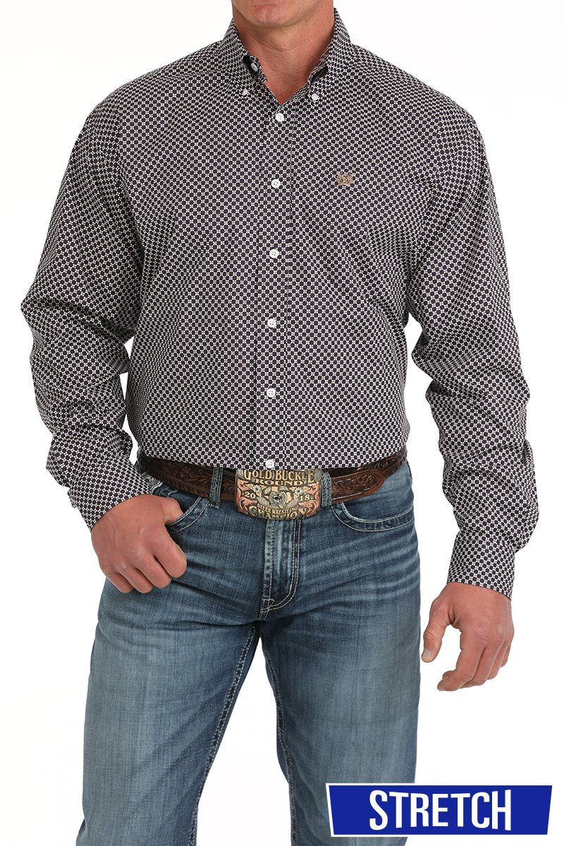Man wearing a black button-down long sleeve western shirt with a white geometric print, paired with blue jeans and a tooled leather belt with a large buckle. The shirt has a button-down collar, chest logo, and is displayed on a white background