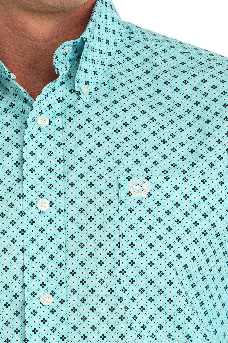 Close-up of a man wearing a turquoise patterned button-down shirt displayed on a white background.