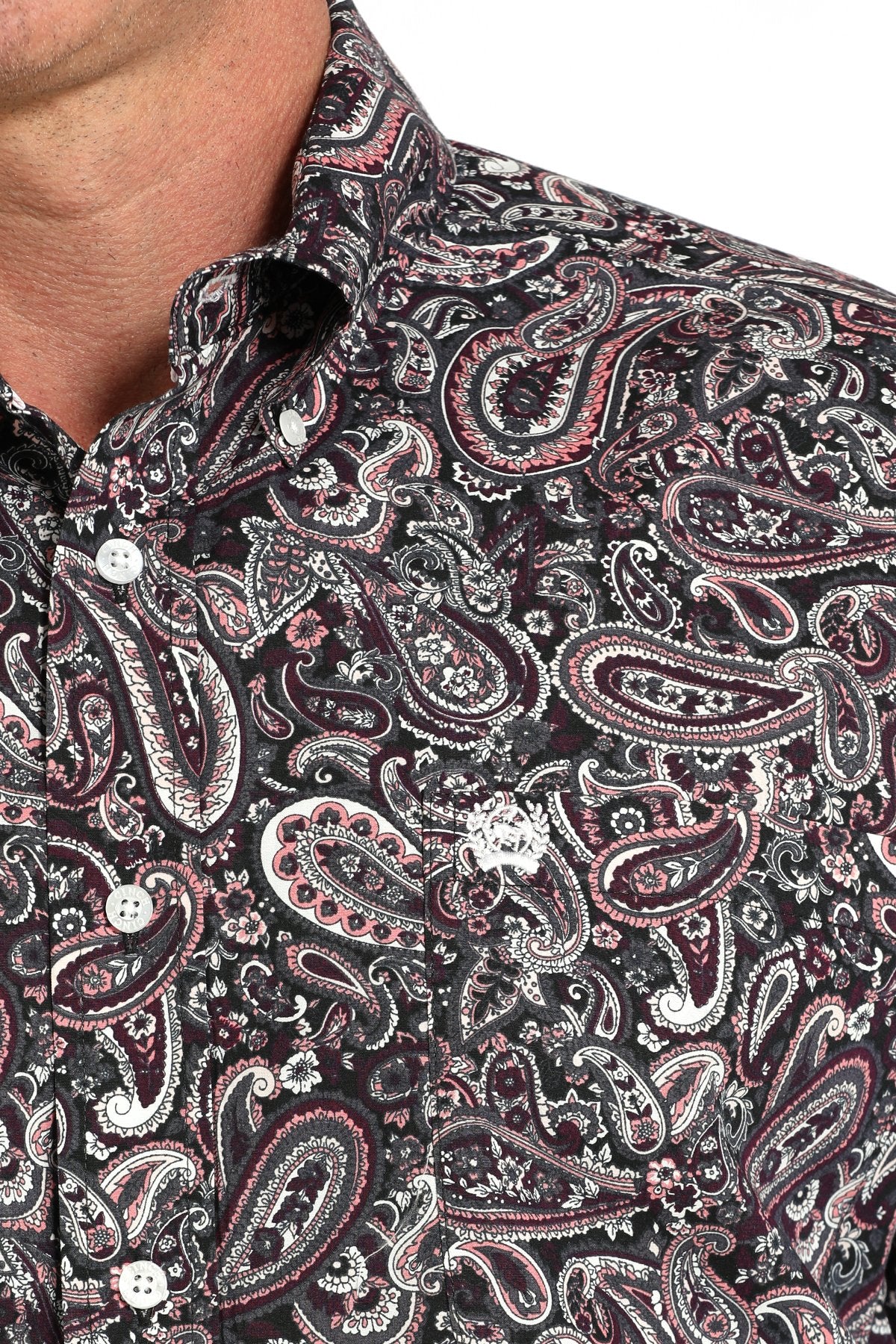 Close-up of a man wearing a long sleeve button-down with a paisley pattern