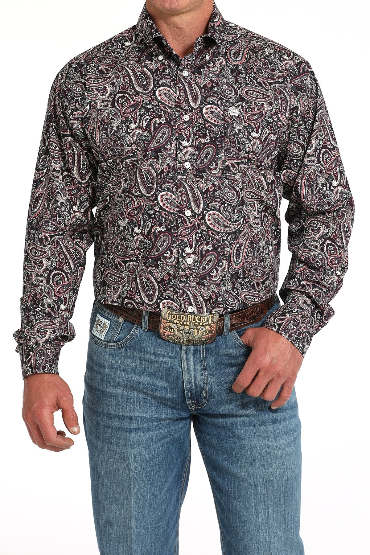 Man wearing a long sleeve button-down with a paisley pattern, paired with jeans and a belt