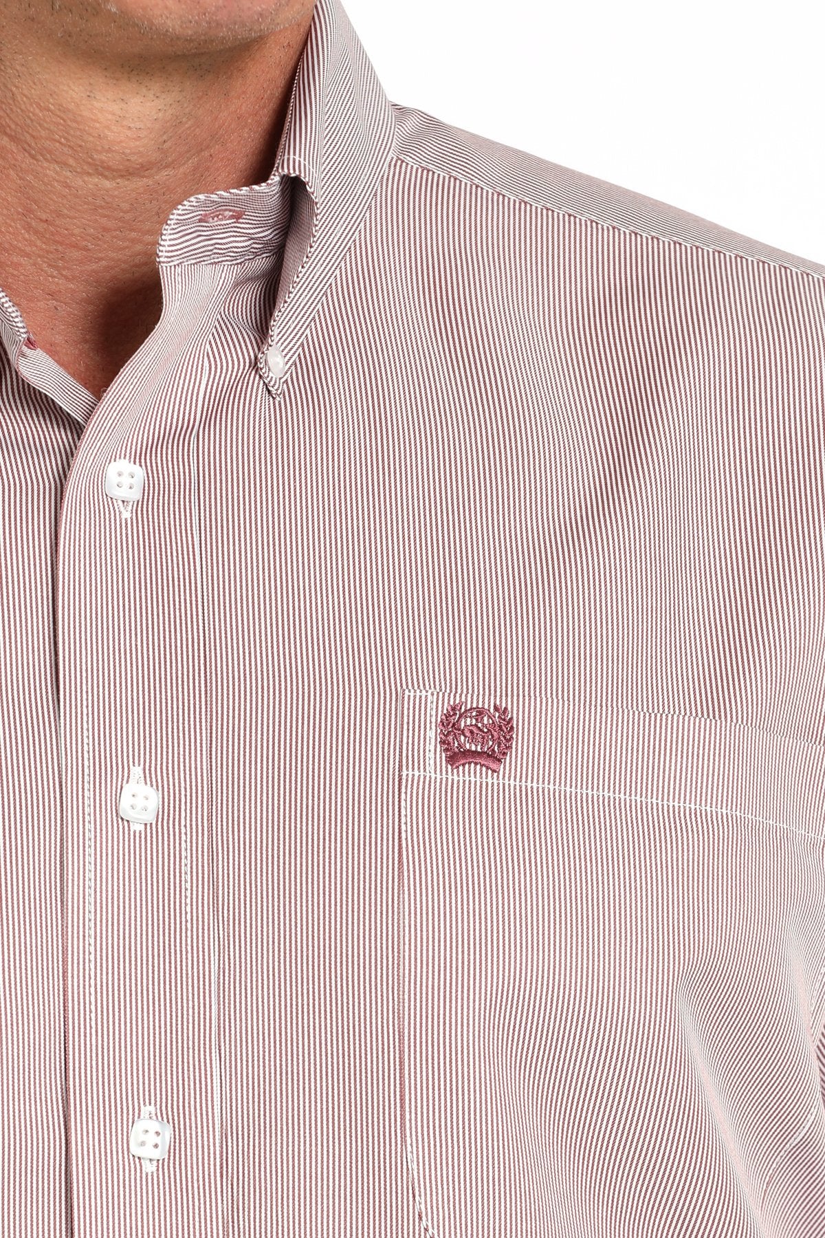 Close-up view of a pink striped long-sleeve button-down shirt with a chest pocket logo displayed on a white background.