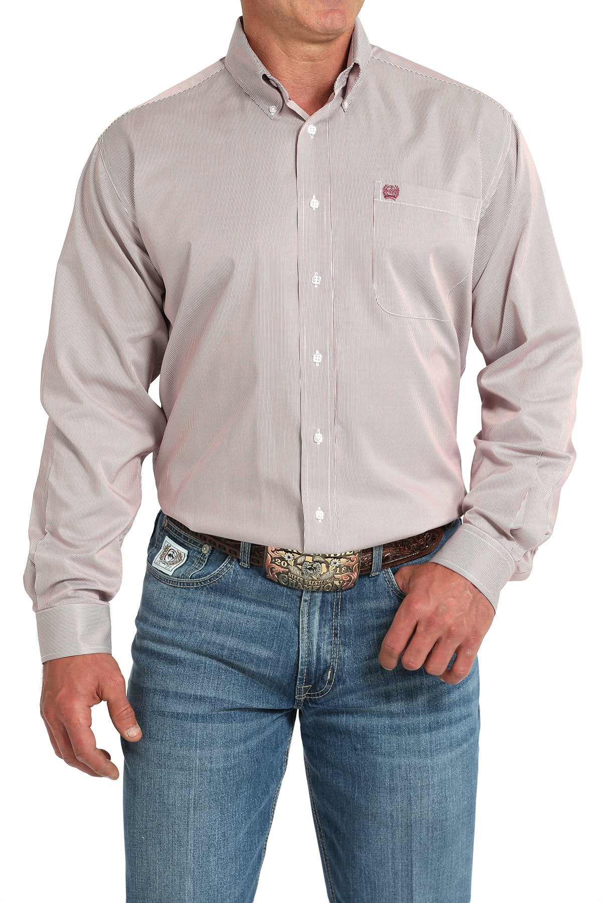 Front view of a man wearing a pink striped long-sleeve button-down shirt with a chest pocket logo, paired with blue jeans and a western belt buckle displayed on a white background.