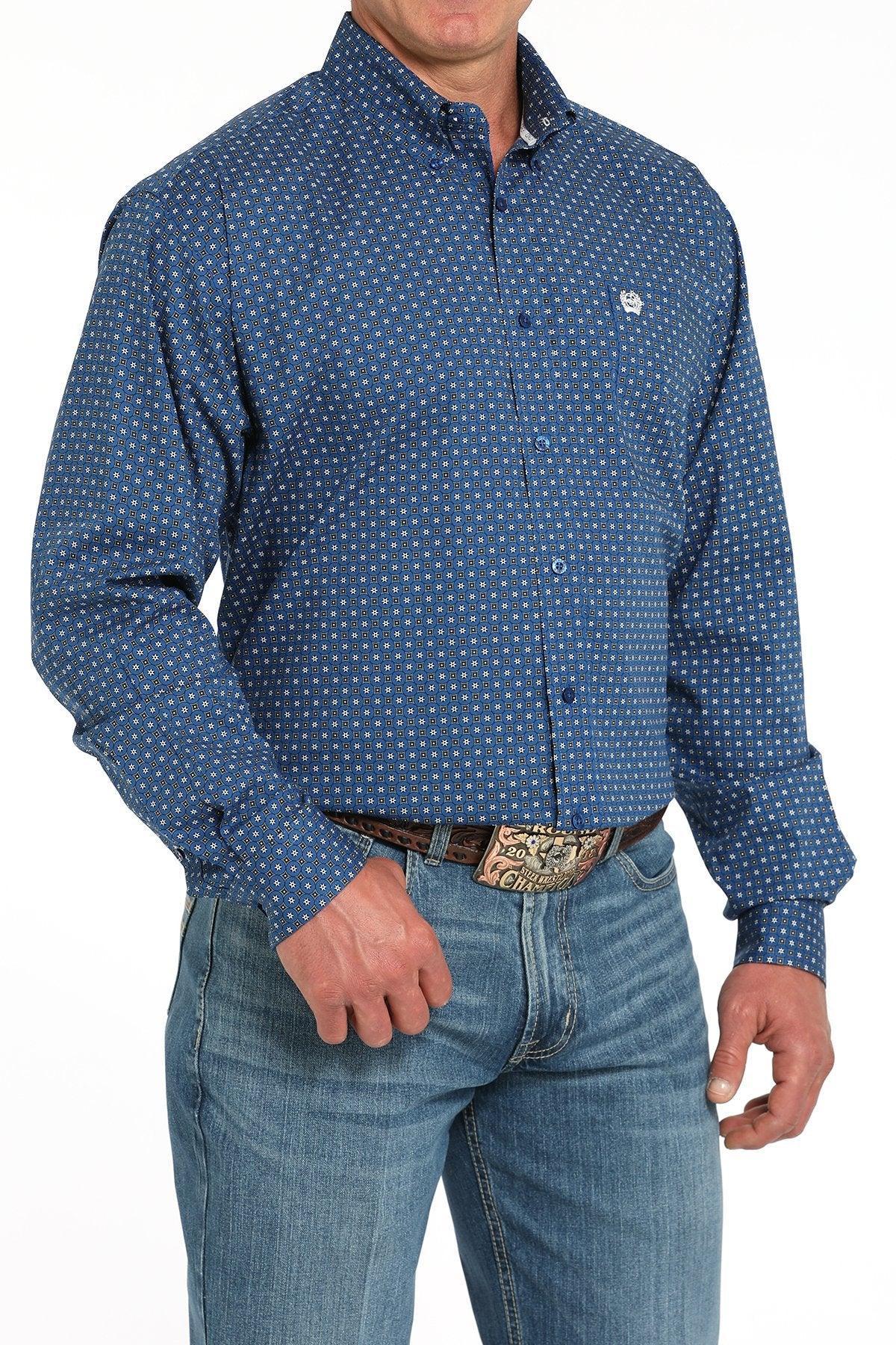 Side angled view of a man wearing a royal blue long-sleeve button-down shirt with a geometric print pattern, paired with blue jeans and a western belt buckle displayed on a white background.