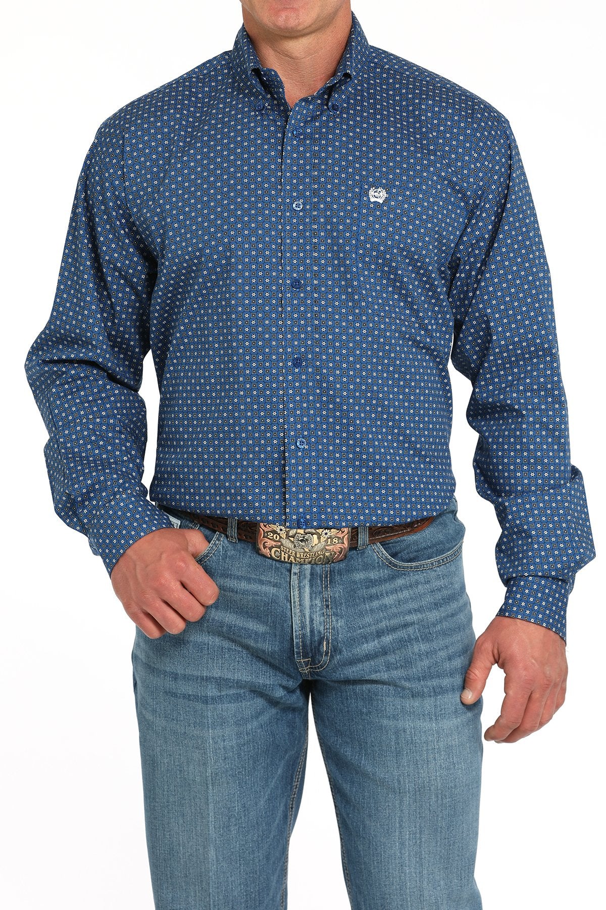 Front view of a man wearing a royal blue long-sleeve button-down shirt with a small geometric print pattern, paired with blue jeans and a western belt buckle displayed on a white background.