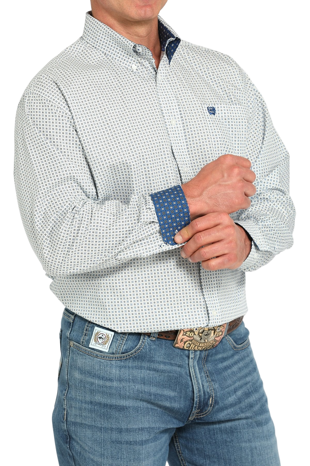 Man wearing a patterned blue long sleeve button-down shirt with contrasting cuffs and jeans on a transparent background