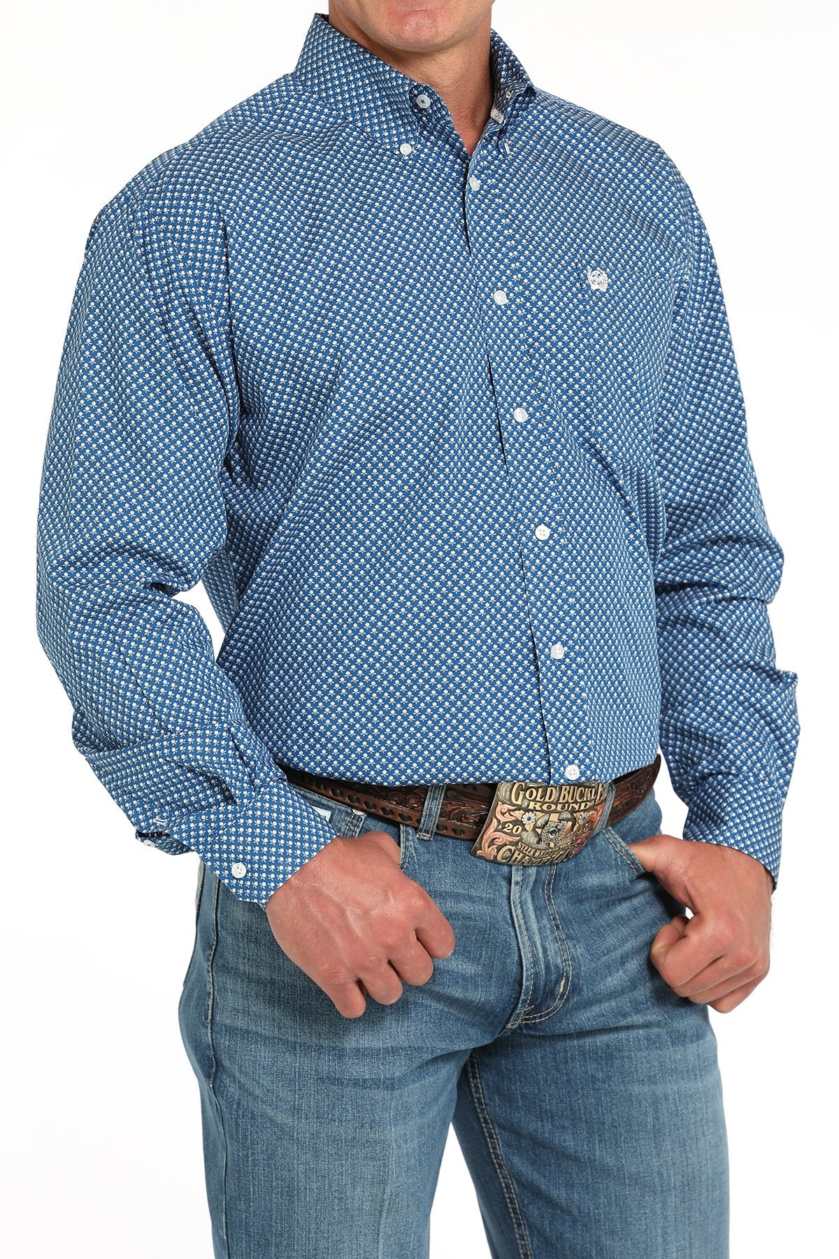 Man wearing a blue patterned button-down shirt tucked into light blue jeans with a western belt buckle displayed on a white background.