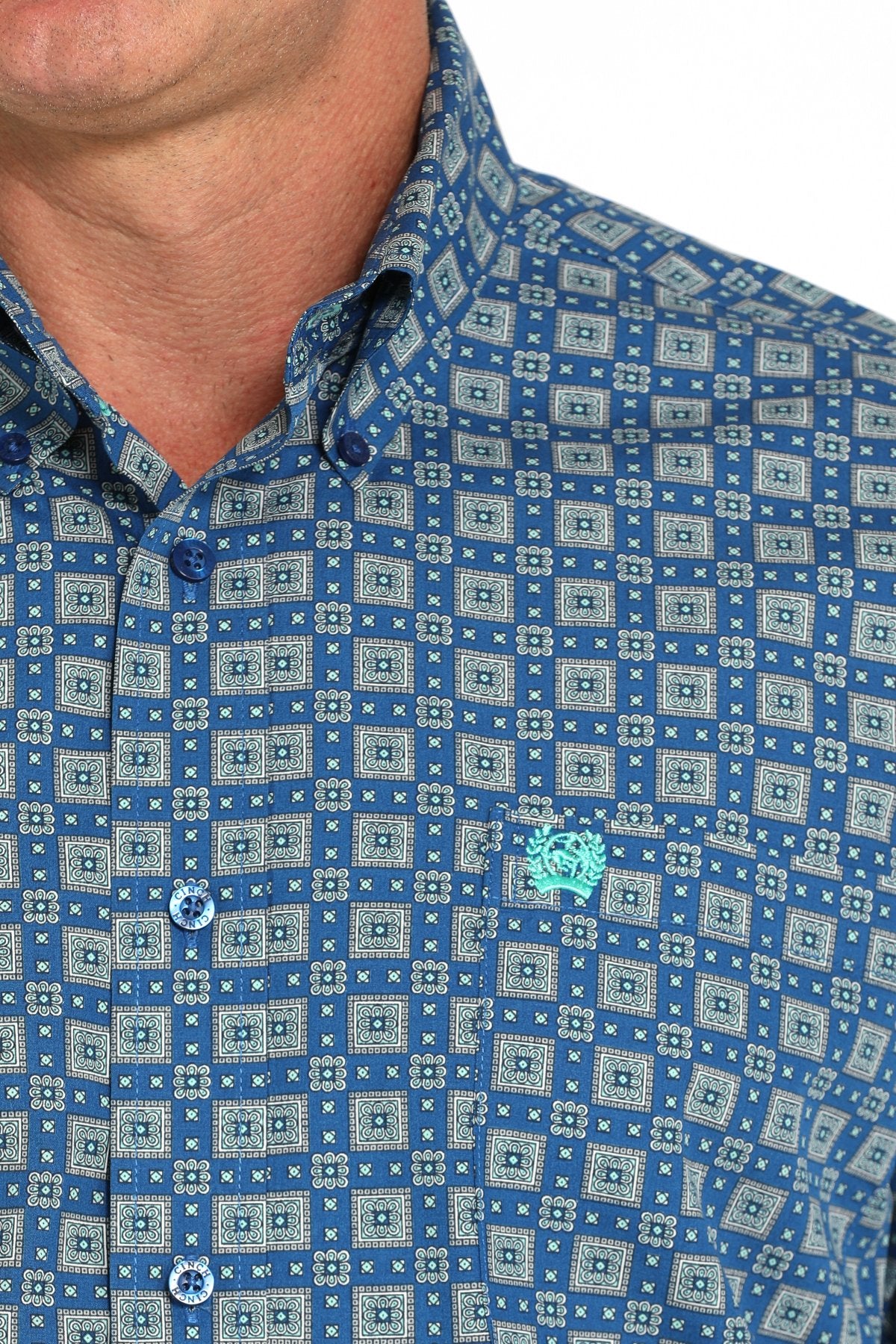 Close-up view of a royal blue long-sleeve button-down shirt with a medallion print pattern displayed on a white background.