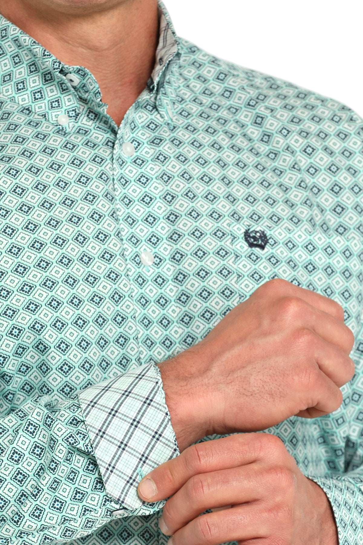 Close-up of a man wearing a patterned blue long sleeve button-down shirt with contrasting cuffs on a transparent background