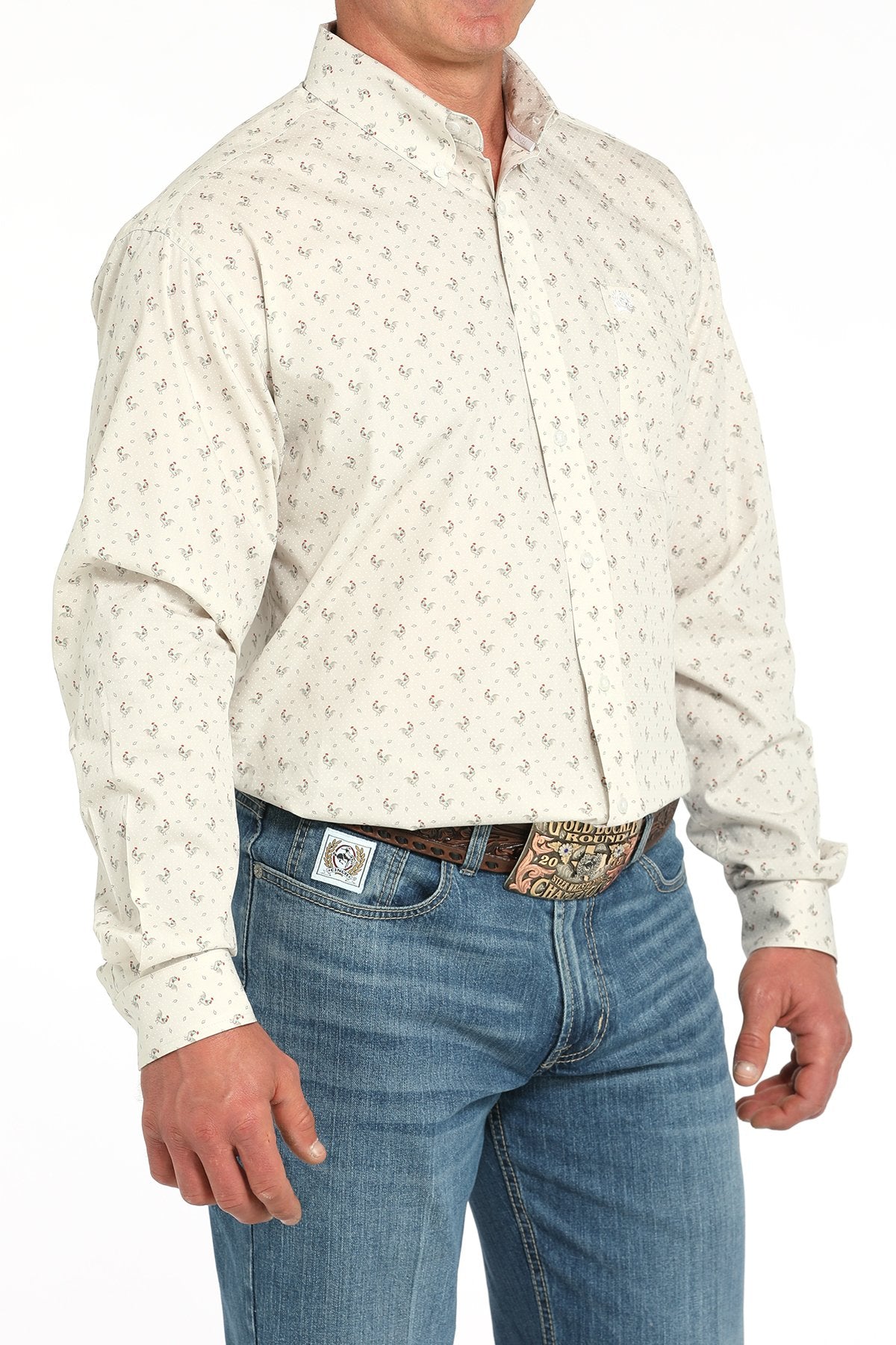 Side angled view of a man wearing a gray long-sleeve button-down shirt with a rooster print pattern, paired with blue jeans and a western belt buckle displayed on a white background.