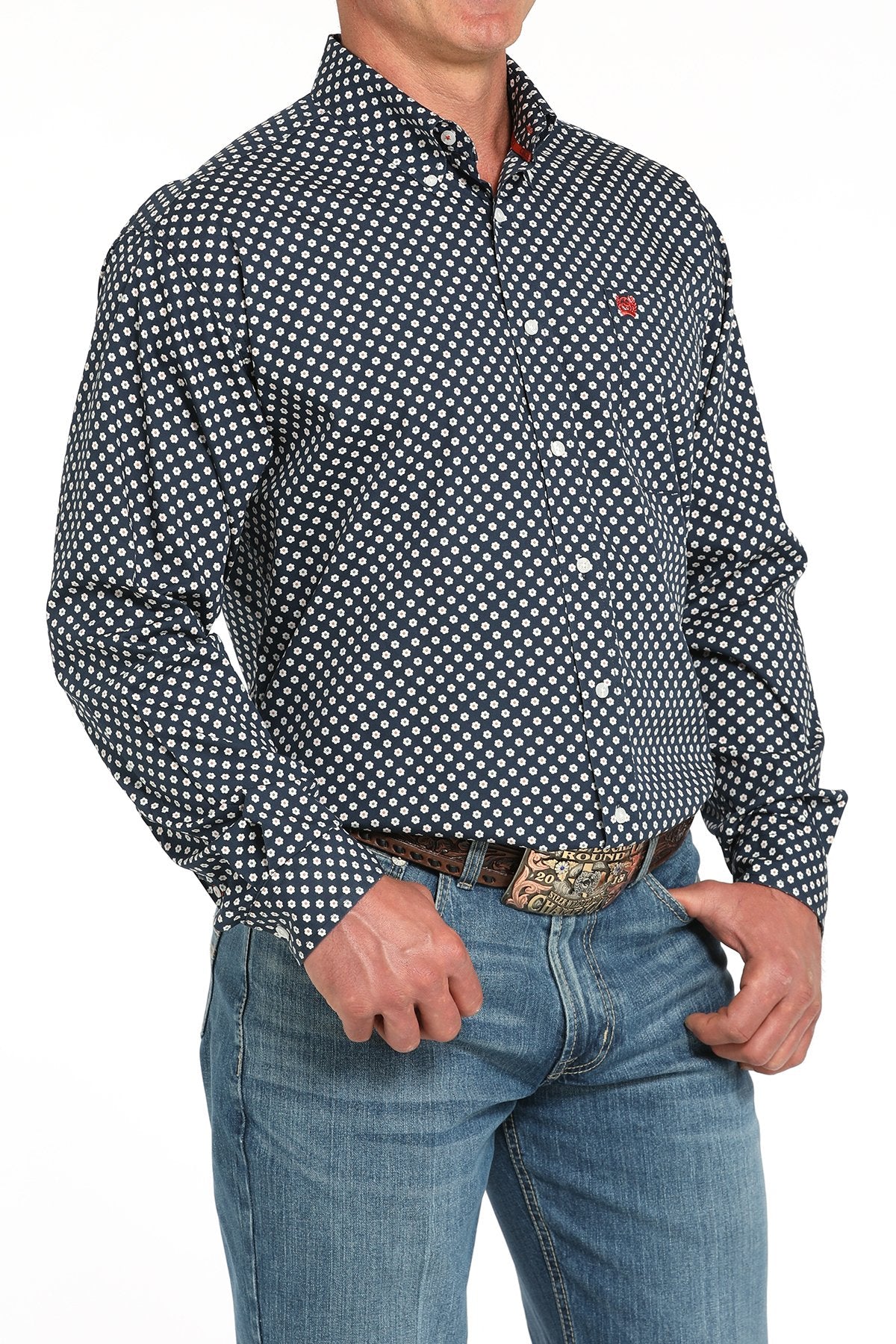 Side angled view of a man wearing a navy long-sleeve button-down shirt with a white daisy print pattern, paired with blue jeans and a western belt buckle displayed on a white background.