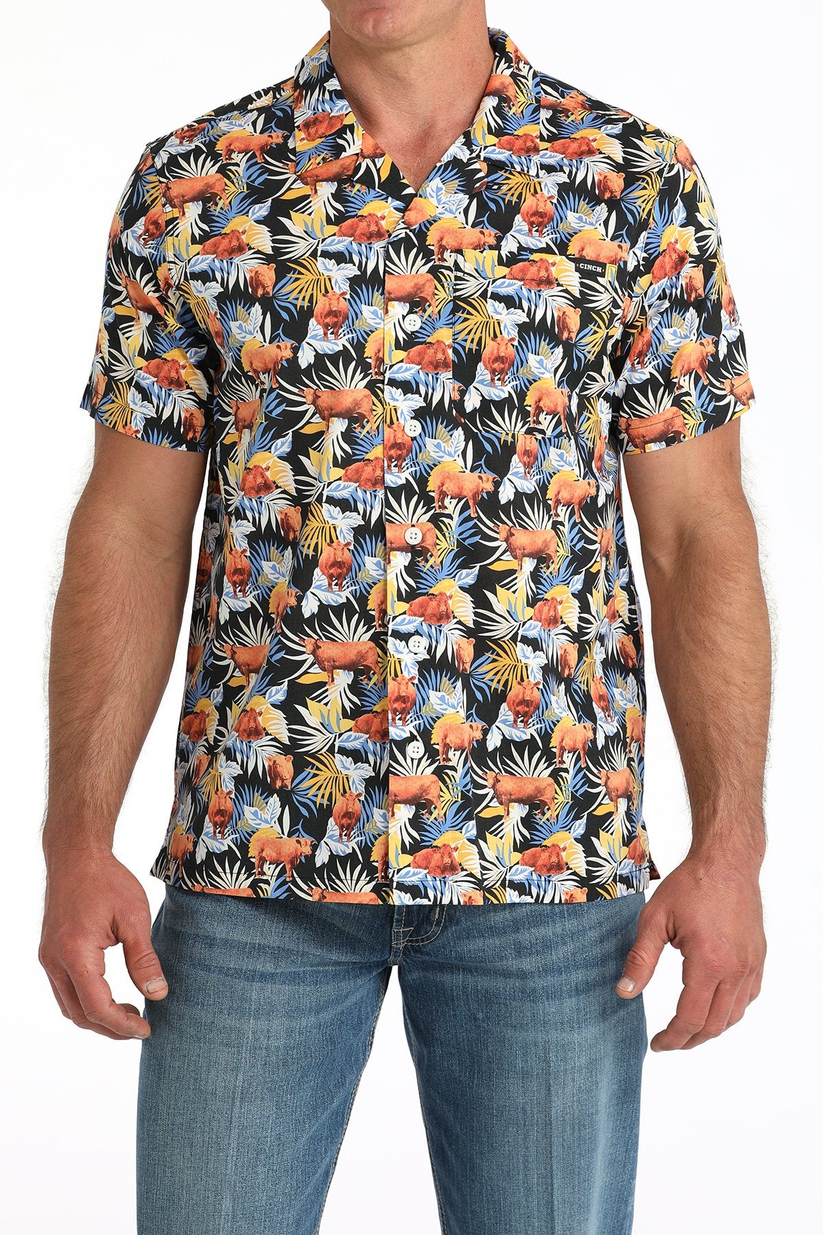 Front view of a man wearing a multicolor tropical print short-sleeve button-down shirt with orange, yellow, and white floral patterns, paired with blue jeans displayed on a white background.