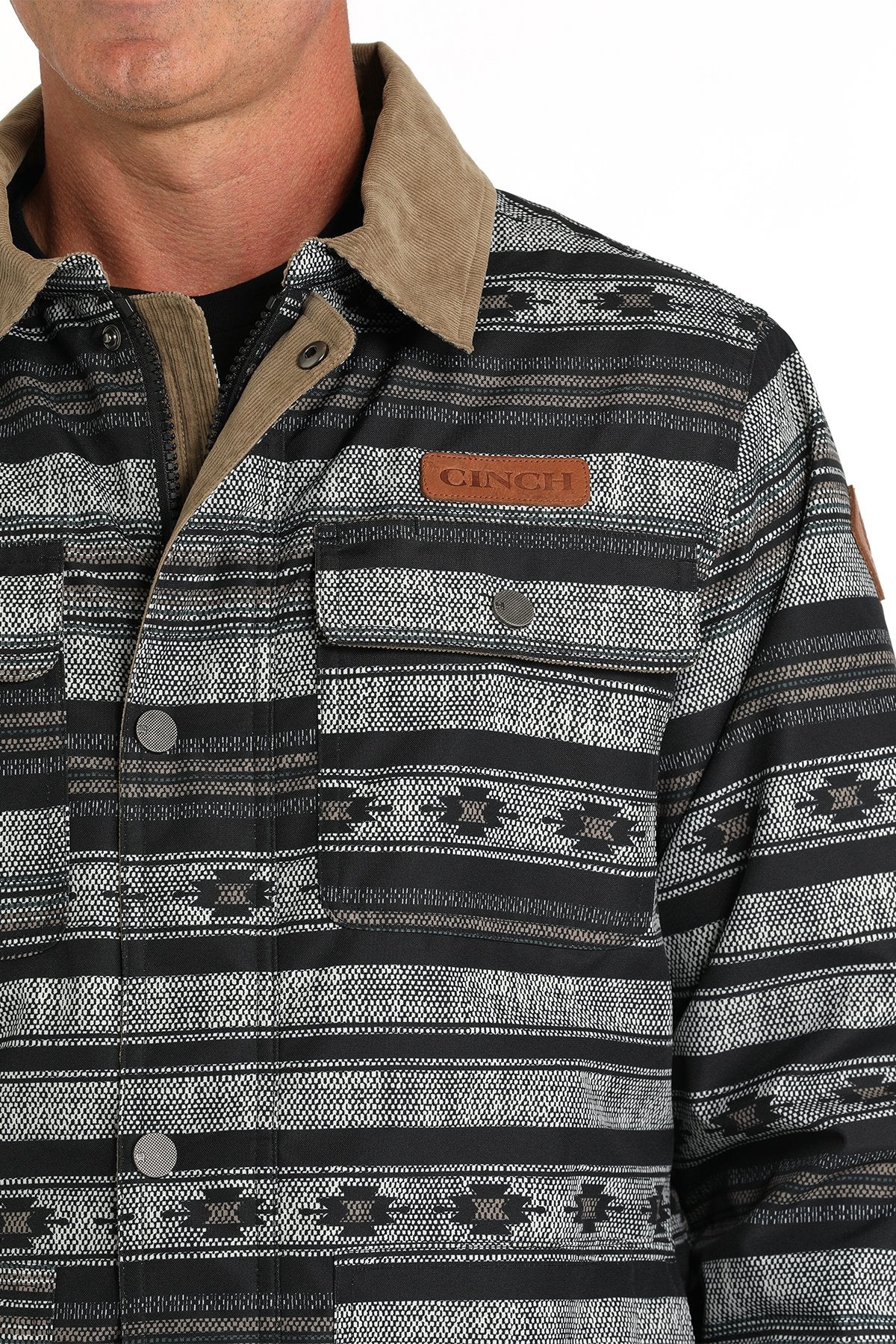 Close-up of a man wearing a black and gray patterned button-up jacket with a hood displayed on a white background.