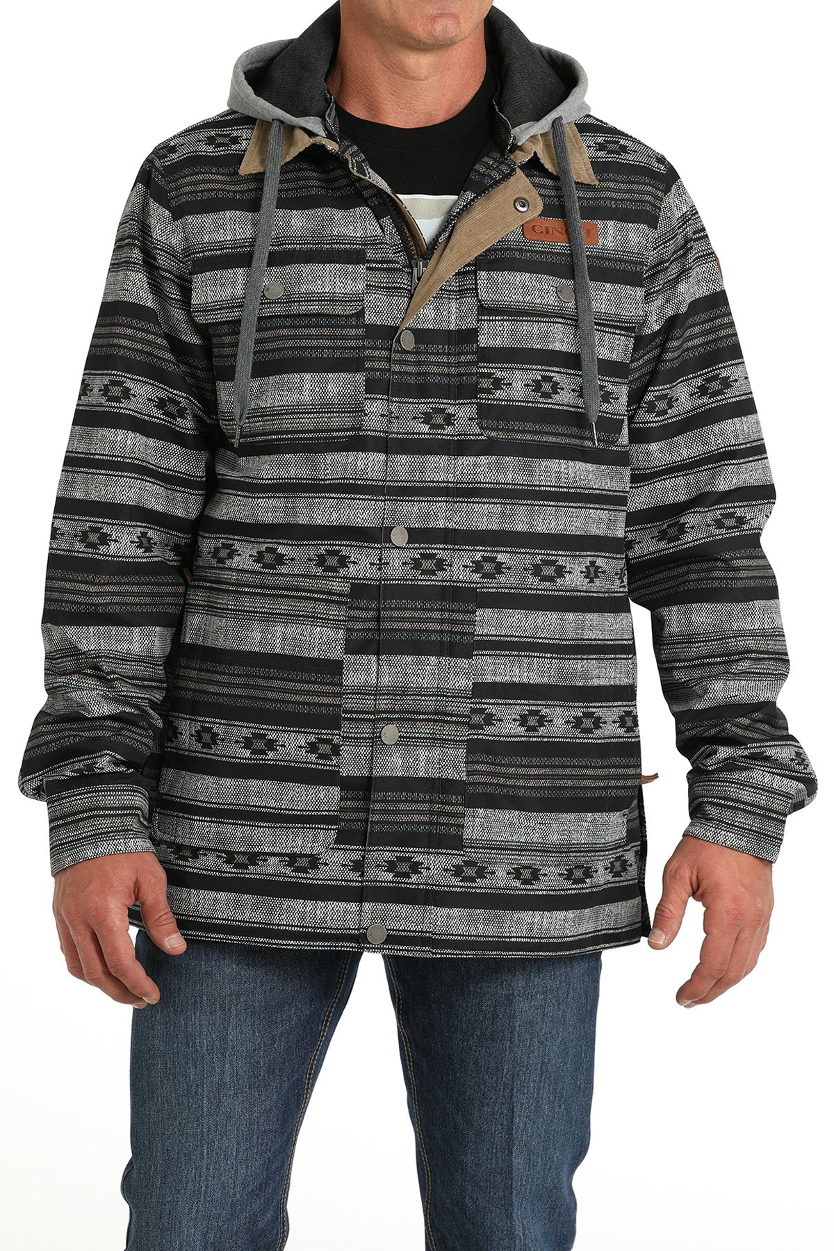 Man wearing a black and gray patterned button-up jacket with a hood and blue jeans displayed on a white background.
