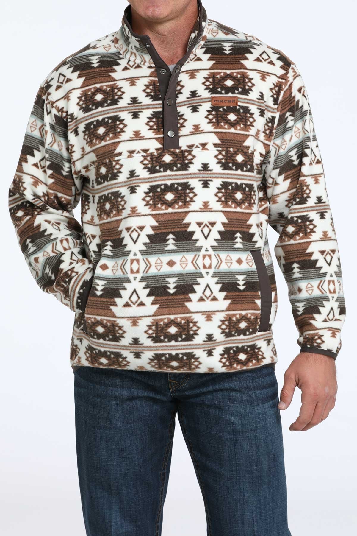 Front view of a man wearing a brown and white Southwestern patterned quarter-zip pullover with blue jeans displayed on a white background.