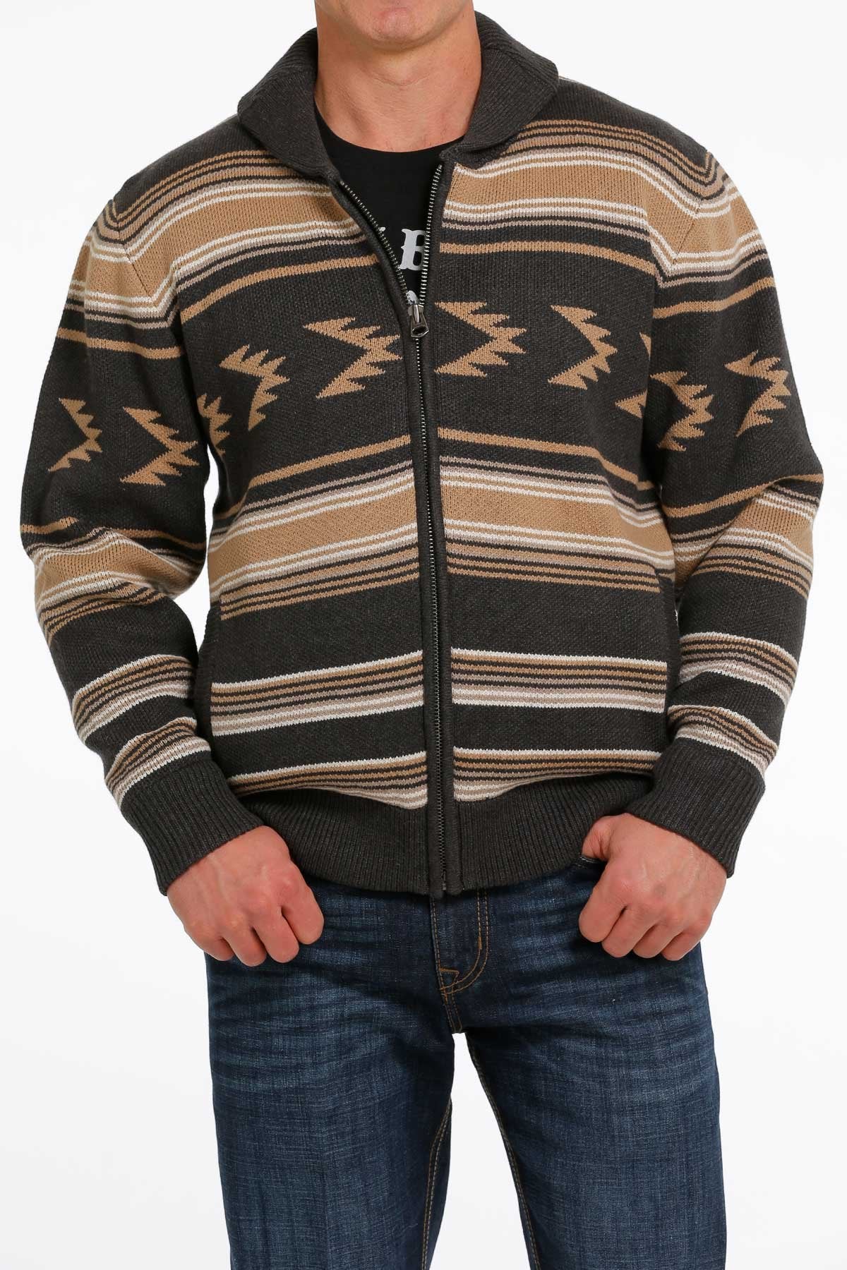 Man wearing a brown and black patterned zip-up sweater jacket with blue jeans displayed on a white background.