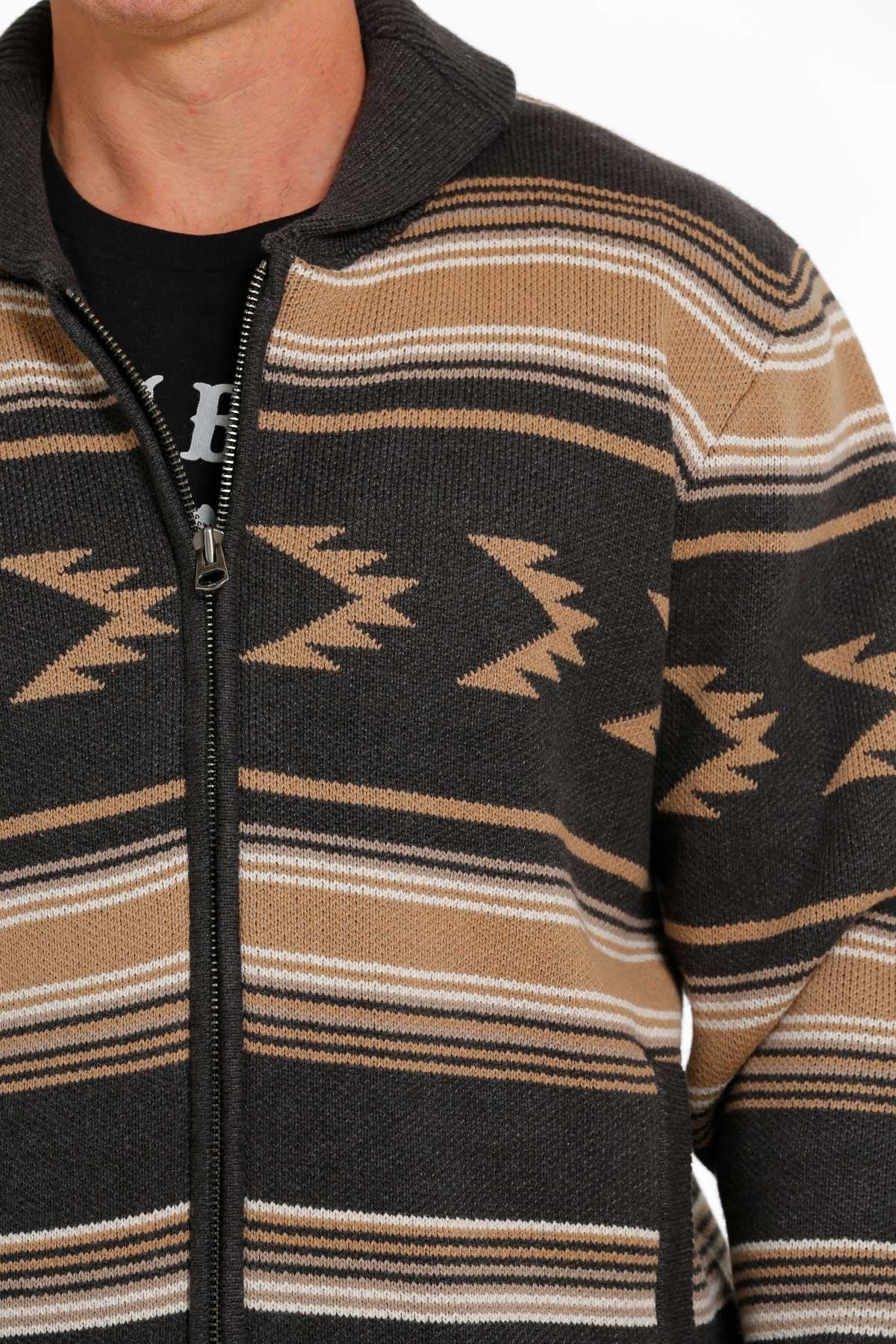 Close-up view of a man wearing a brown and black patterned zip-up sweater jacket displayed on a white background.
