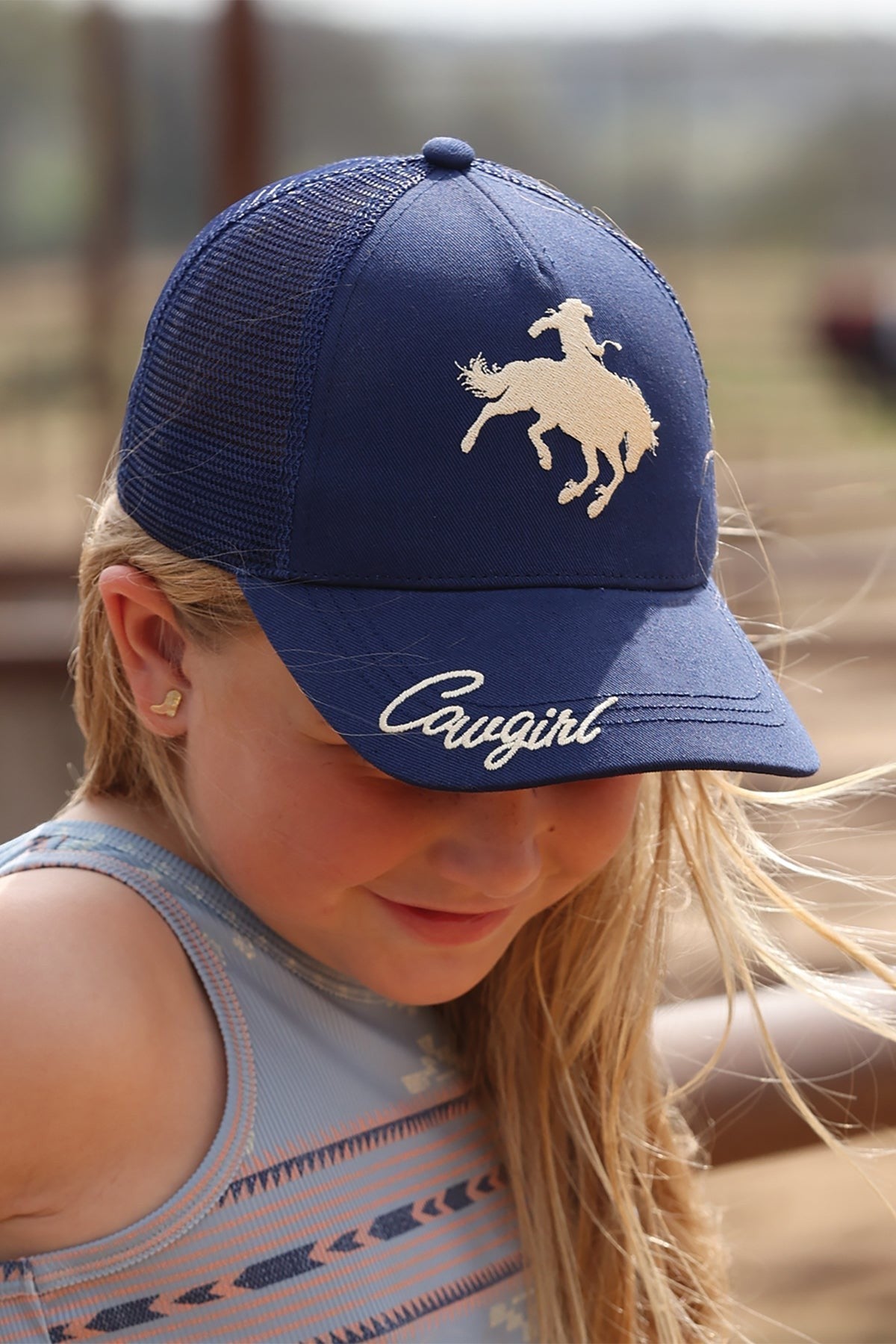 Go West Supply blue trucker cap with embroidered bucking bronco and "Cowgirl" script. Mesh back for breathability.