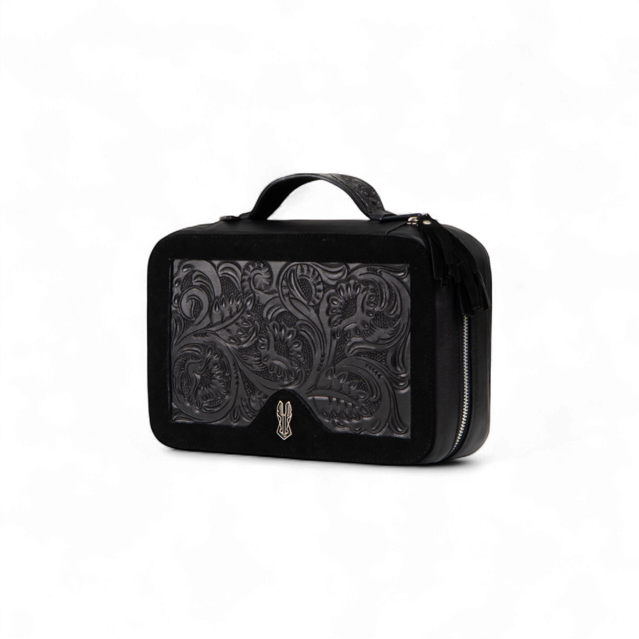 Black rectangular toiletry bag with a tooled leather floral design on the front panel, a small handle on top, and a silver zipper with tassel accents on the side
