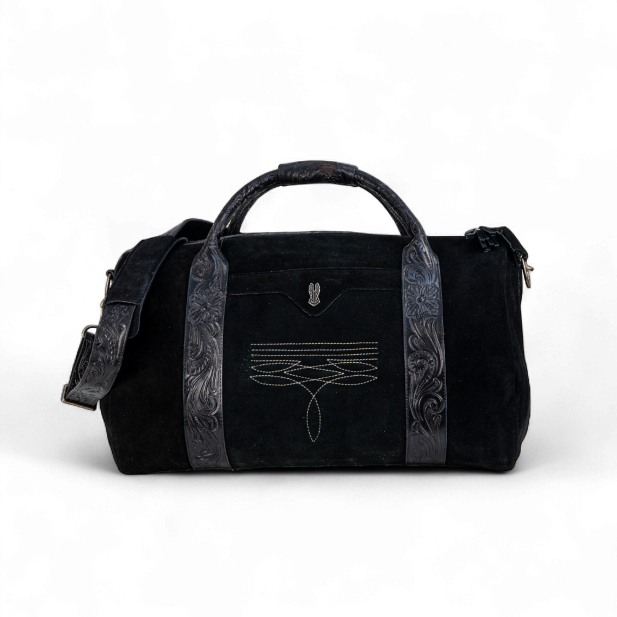 Black suede duffel bag with tooled leather handles and trim, featuring decorative stitching on the front panel. The bag includes an adjustable shoulder strap and a structured silhouette